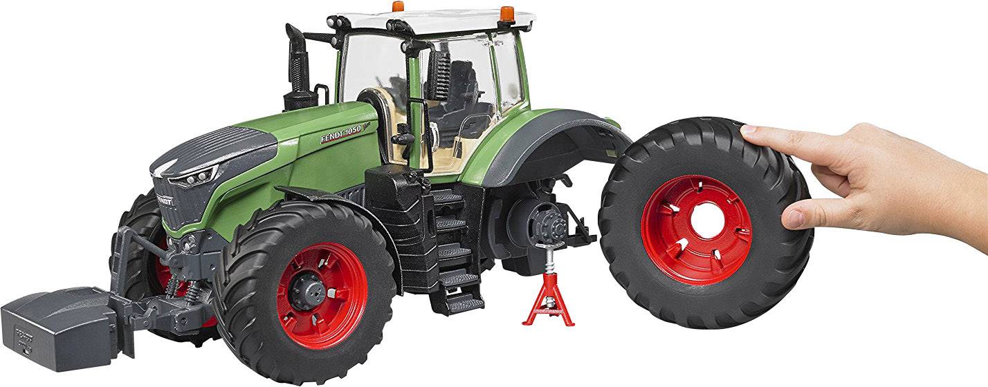 Ein großer grüner Spielzeugtraktor mit abnehmbaren Reifen. Eine Hand hält einen der Reifen.