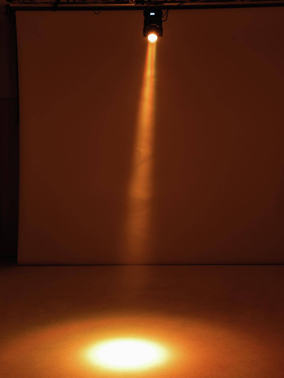 Ein einzelner Scheinwerfer strahlt einen Lichtkegel auf den Boden, umgeben von Dunkelheit.