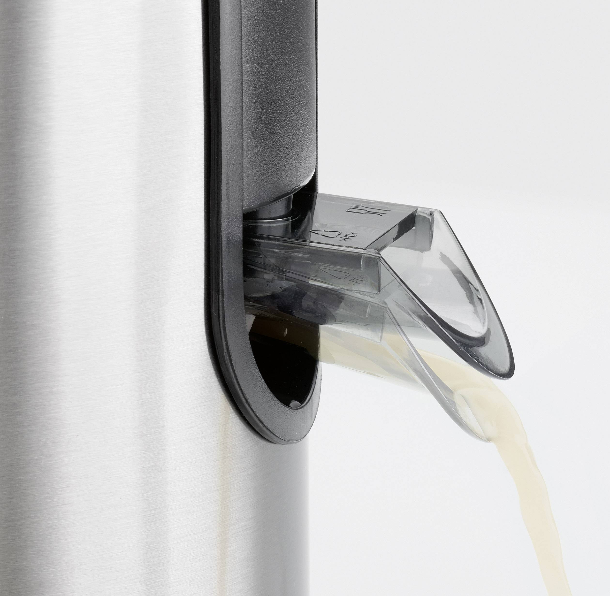 Nahaufnahme eines elektrischen Zitrusentsafters aus Edelstahl in Aktion, beim Ausgießen von Saft aus dem Ausguss.