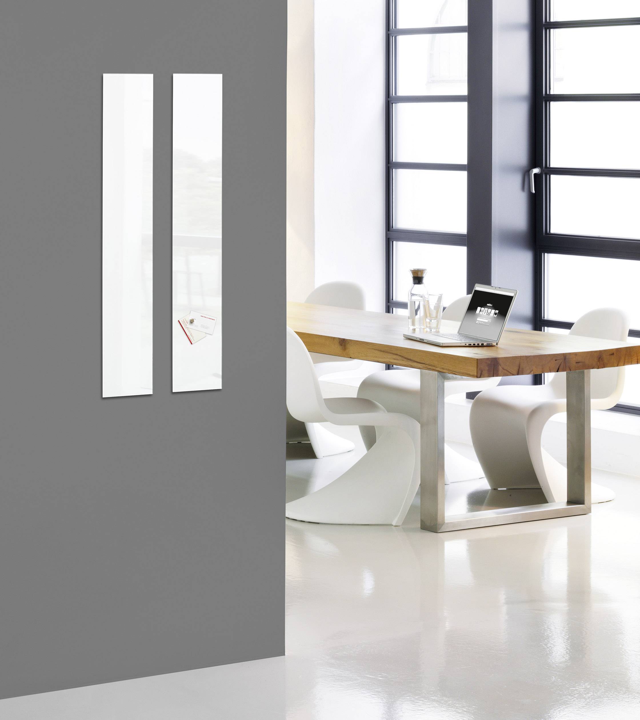 Moderner Besprechungsraum, Holztisch mit weißen Stühlen. Große Fenster sorgen für viel Tageslicht. Im Hintergrund minimalistisches Design.