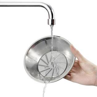 Eine Hand hält ein rundes metallenes Sieb unter fließendem Wasser aus einem Wasserhahn.