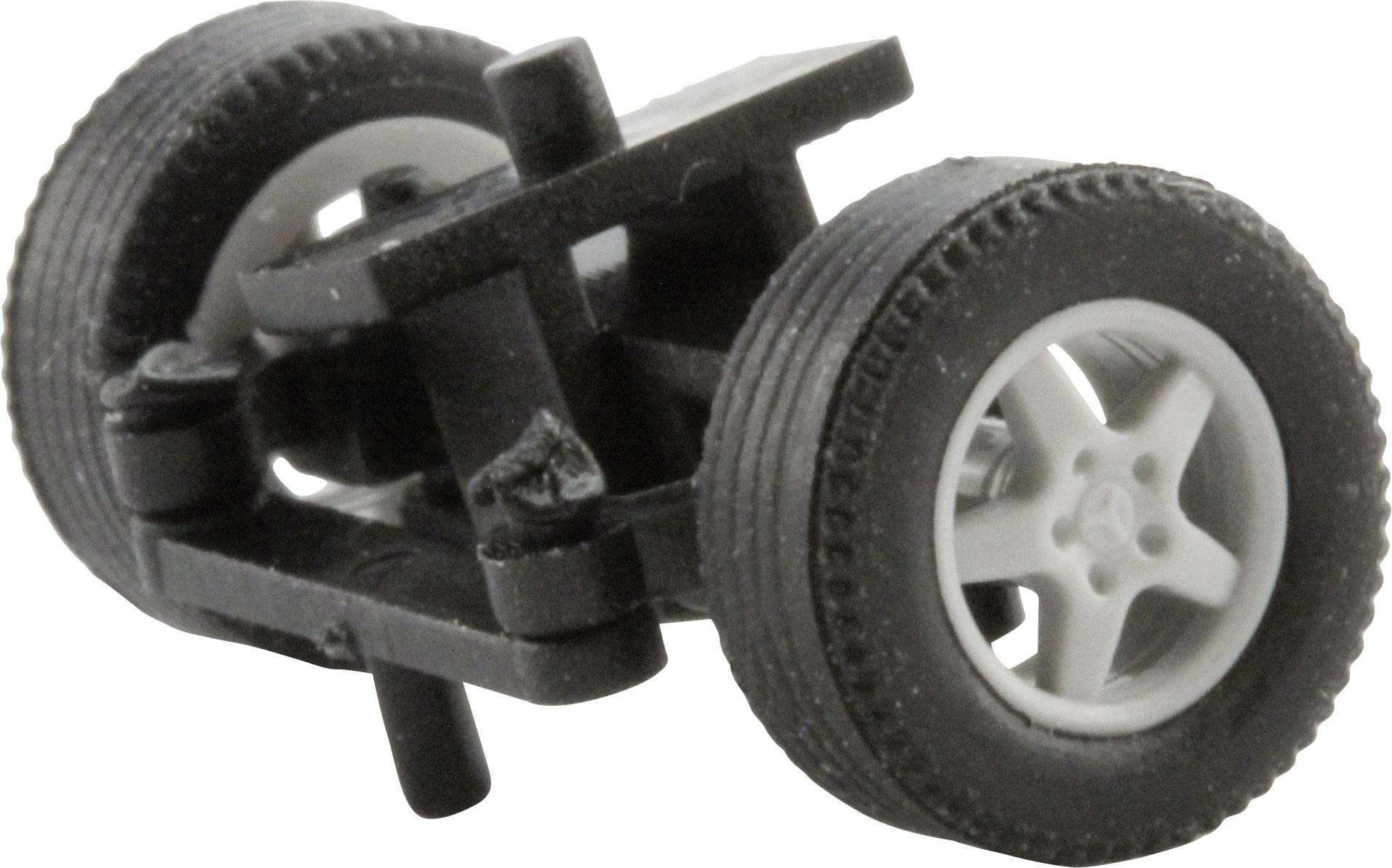 Zwei schwarze Spielzeugräder mit weißen Felgen sind mit einer schwarzen Kunststoffachse verbunden, auf einer weißen Oberfläche.