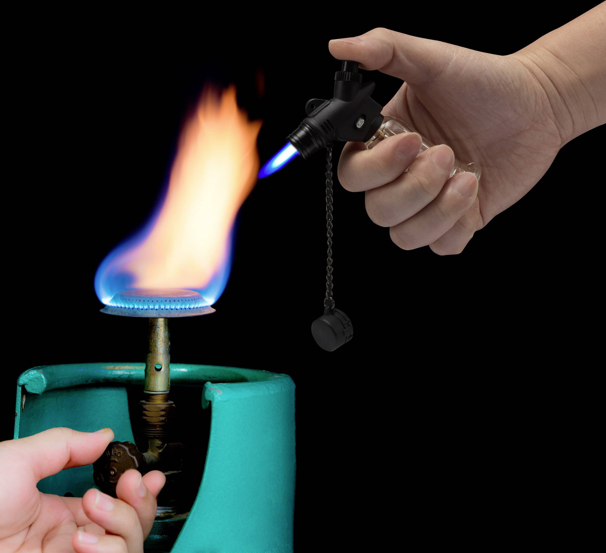Eine Hand hält einen Gasanzünder, die eine blaue Flamme erzeugt, während eine andere Hand einen Gasbrenner öffnet.