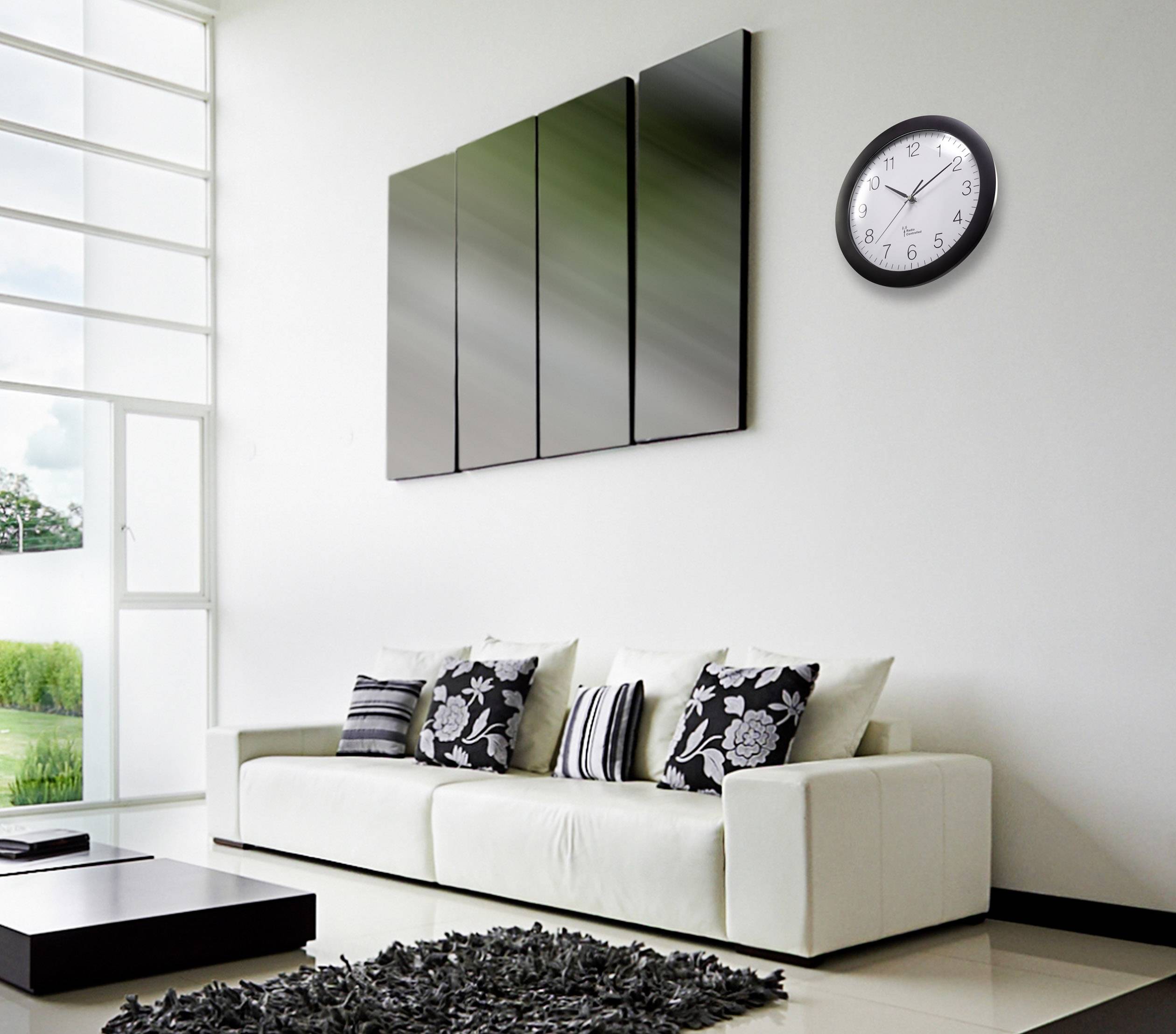 Modern eingerichtetes Wohnzimmer mit weißem Sofa, dekorativen Kissen, moderner Kunst an der Wand und einer Uhr, die 10:09 Uhr zeigt.
