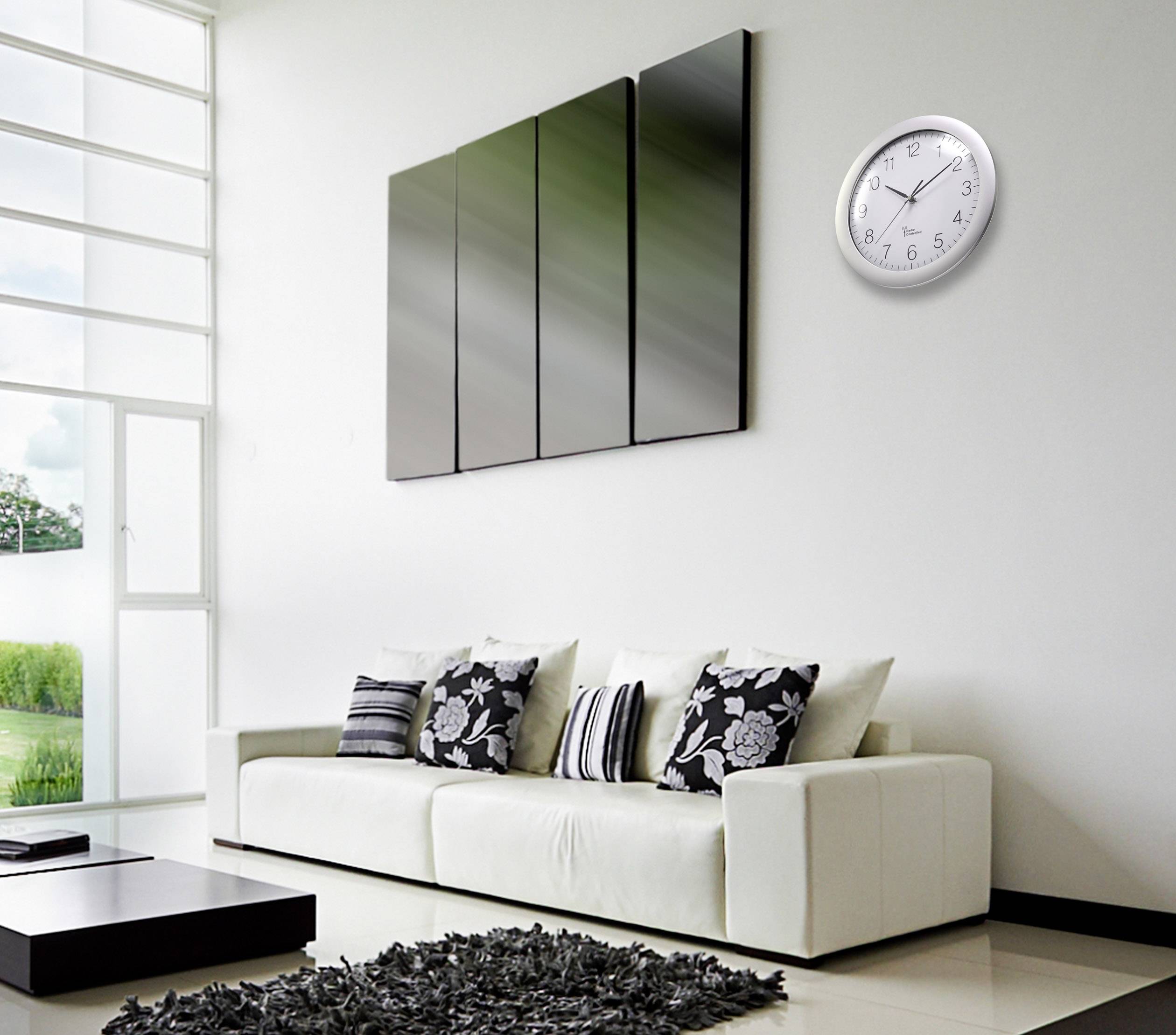 Ein modernes Wohnzimmer mit weißem Sofa, dekorativen Kissen, abstraktem Wandbild und einer runden Wanduhr.