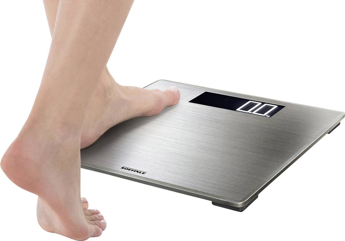 Person stellt einen Fuß auf eine digitale Körperwaage mit Edelstahloberfläche. Waage zeigt zwei Nullstellen auf der Anzeige.