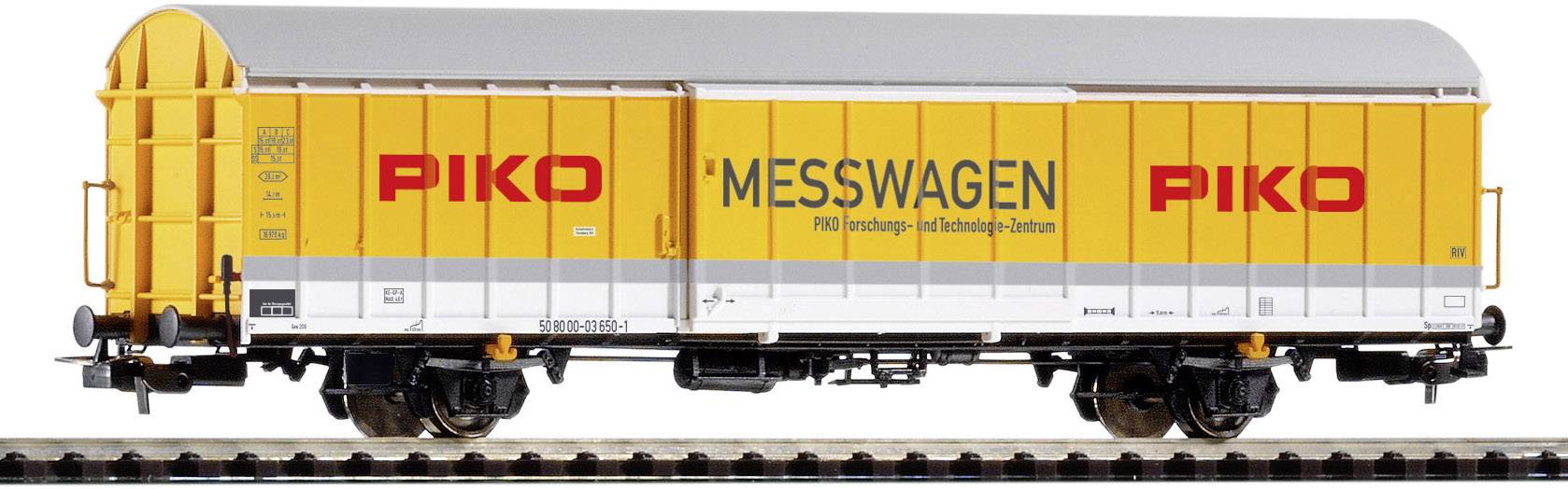 Gelber PIKO-Messwagen auf Gleisen, beschriftet mit 'PIKO' und 'MESSWAGEN'. Modell eines Güterwagens zur Vermessung von Eisenbahnstrecken.