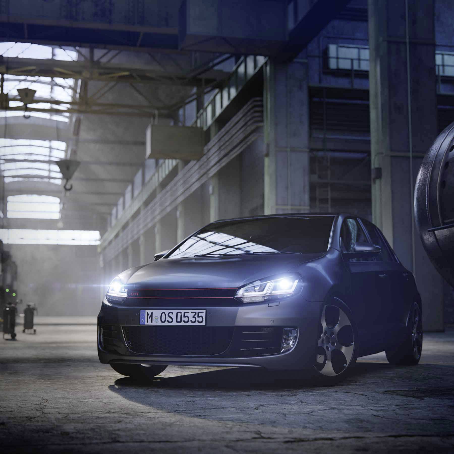 Ein dunkelblauer Kleinwagen steht in einer großen, industriell wirkenden Halle mit hohen Fenstern und einfallendem Licht.