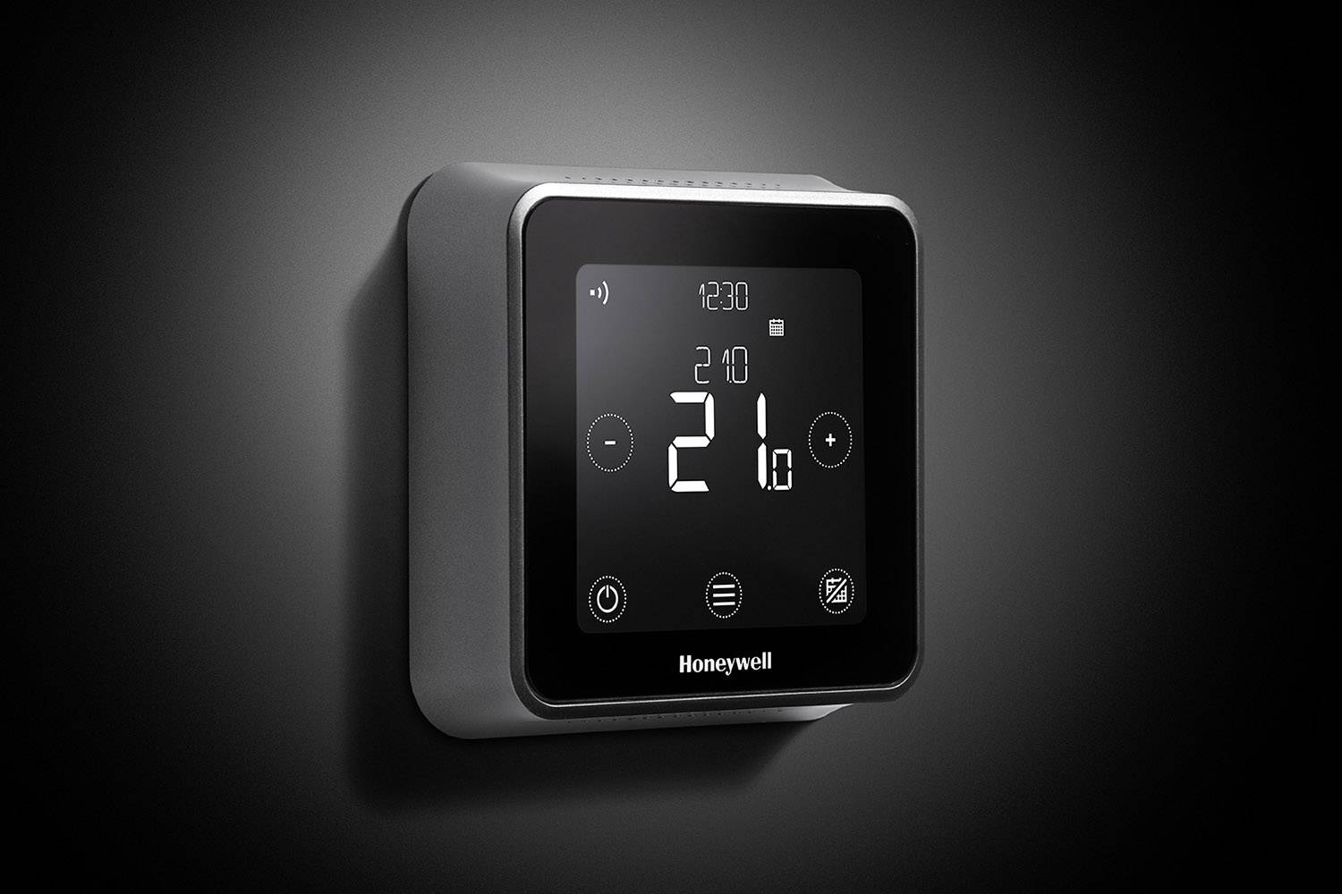 Ein digitales Thermostat an der Wand zeigt eine Temperatur von 21 Grad Celsius an. Es hat eine moderne, quadratische Form.