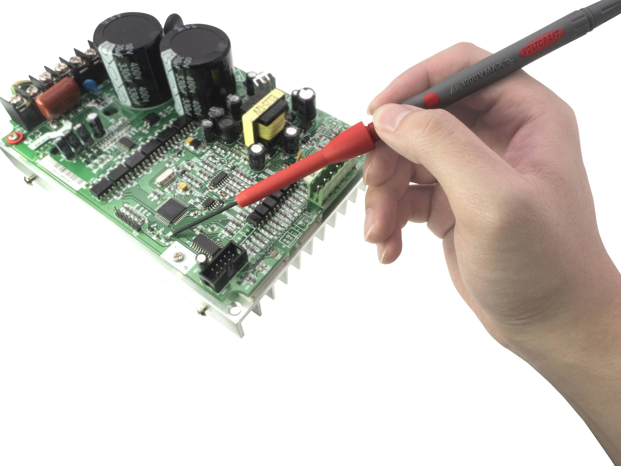 Eine Hand hält ein Prüfgerät und arbeitet an einer grünen Leiterplatte mit verschiedenen elektronischen Komponenten und Schaltungen.