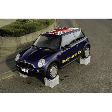 Ein blauer Mini Cooper steht auf grauen Plastikboxen. Auf der Seite des Autos steht 'Really Useful Box'. Das Dach zeigt die britische Flagge.
