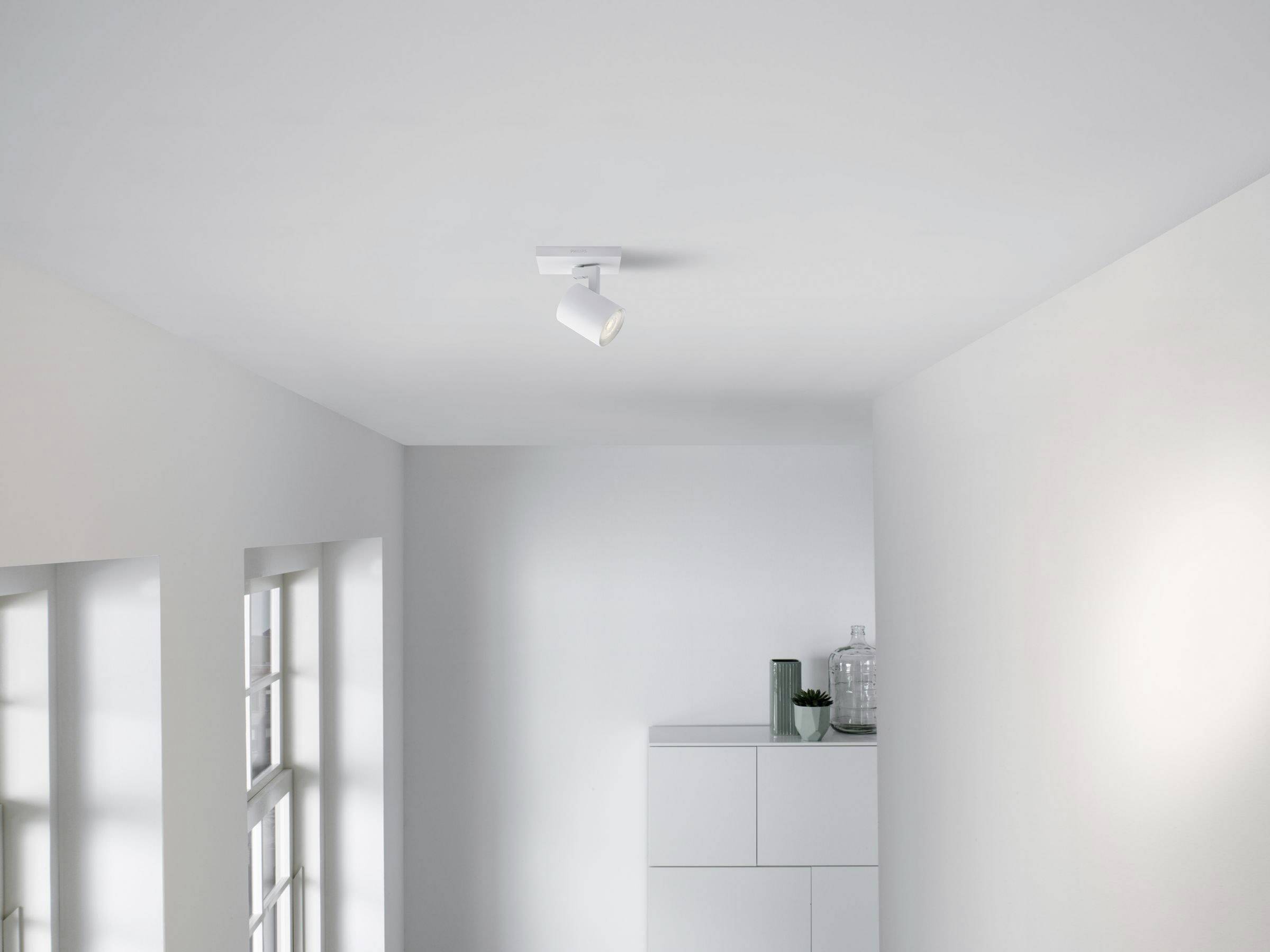 Ein minimalistisch gestaltetes Zimmer mit weiß gestrichenen Wänden und Decke. An der Decke ist ein einzelnes Spotlicht angebracht.