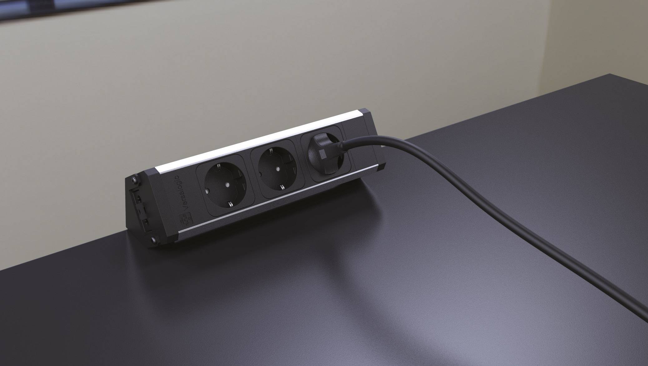 Ein schwarzes Kabel ist an eine Steckdosenleiste mit zwei Steckplätzen auf einem Tisch angeschlossen. Die Umgebung sieht modern aus.
