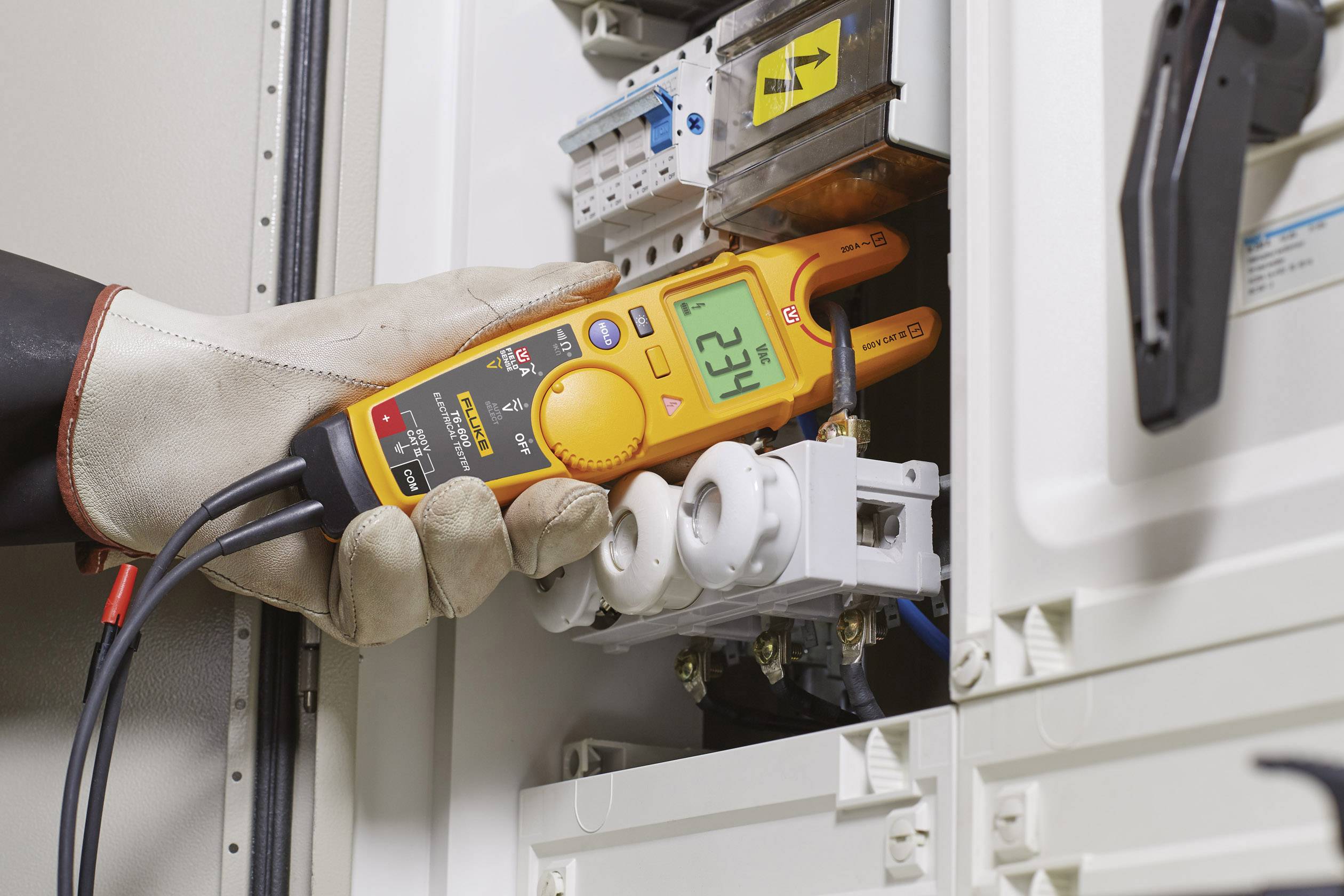 Eine behandschuhte Person misst mit einem Multimeter die elektrische Spannung in einem Schaltschrank. Das Display zeigt '625 V'.