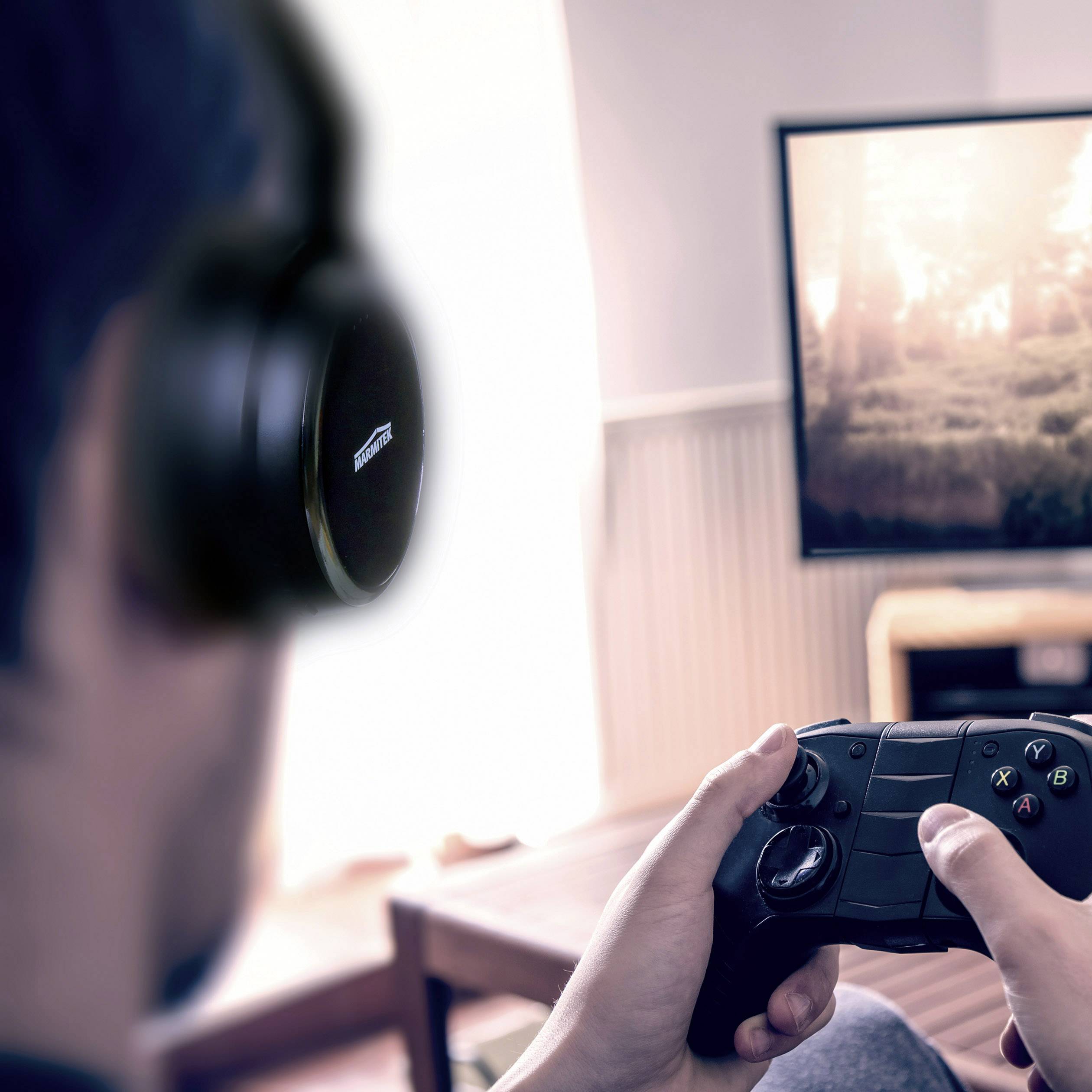 Eine Person mit Kopfhörern hält einen Controller, während sie auf einen verschwommenen Bildschirm mit einem Videospiel blickt.