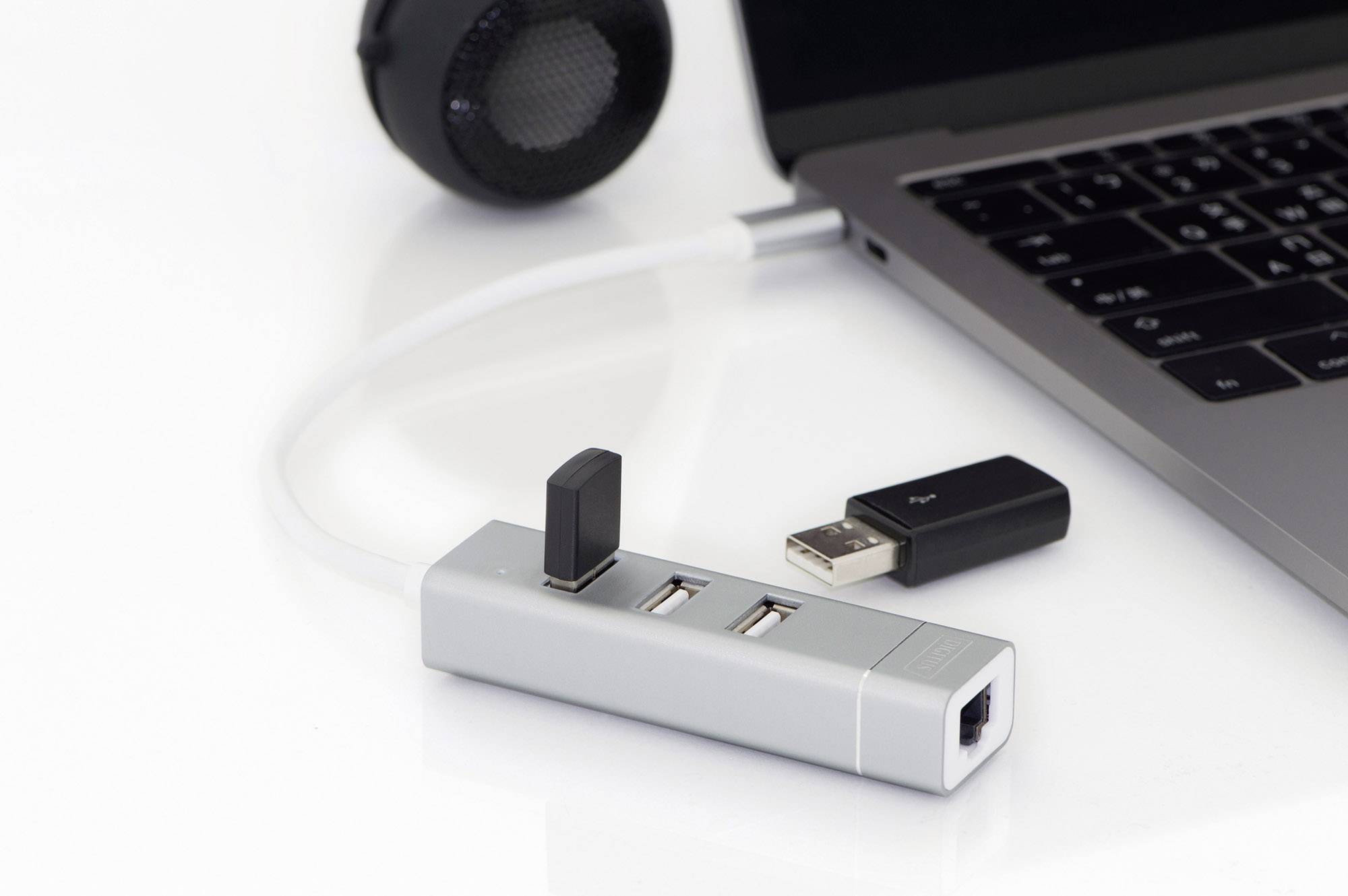 USB-Hub mit mehreren USB-Sticks und einem Netzwerkkabel, verbunden mit einem Laptop, daneben ein Lautsprecher.