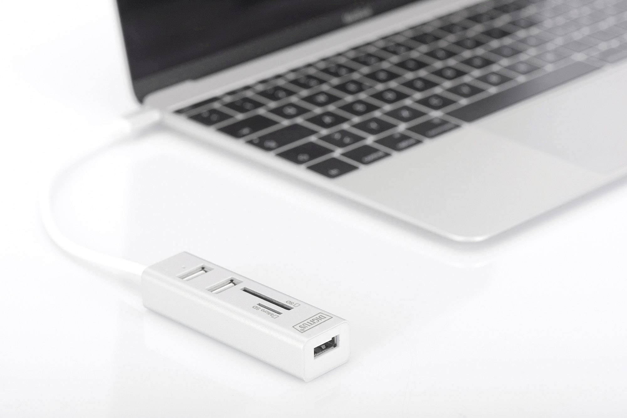 Ein Laptop mit einem angeschlossenen weißen USB-Hub, der mehrere USB-Anschlüsse und Kartenschächte bietet.