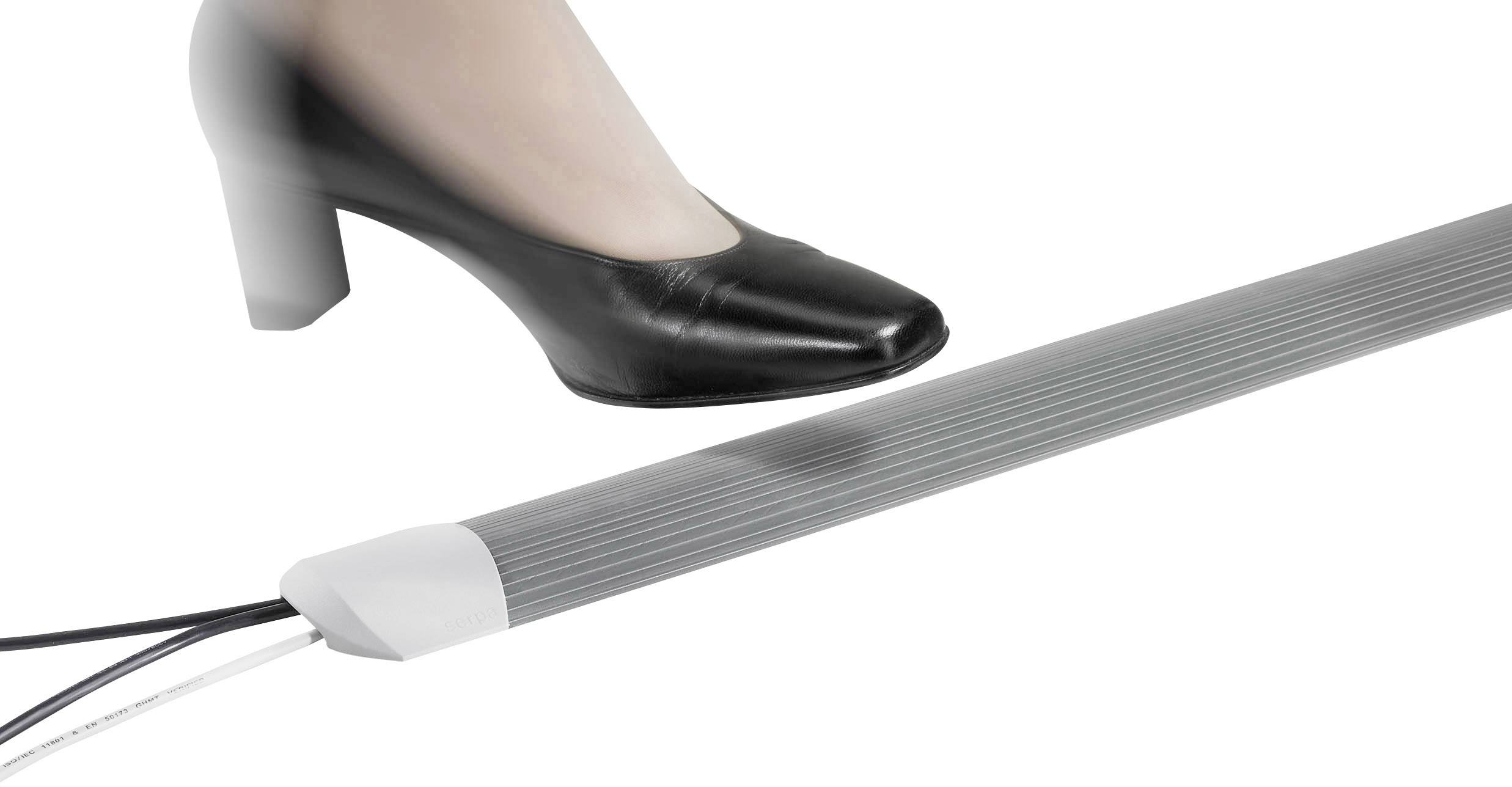 Eine Person tritt mit einem schwarzen Schuh auf eine flexible metallische Oberfläche mit Kabeln, die auf Druck reagiert.