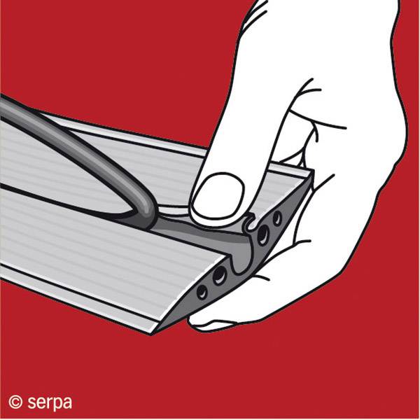 Hand hält ein Aluminiumprofil, während ein schwarzer Gummistreifen in eine Nut eingeführt wird. Roter Hintergrund.