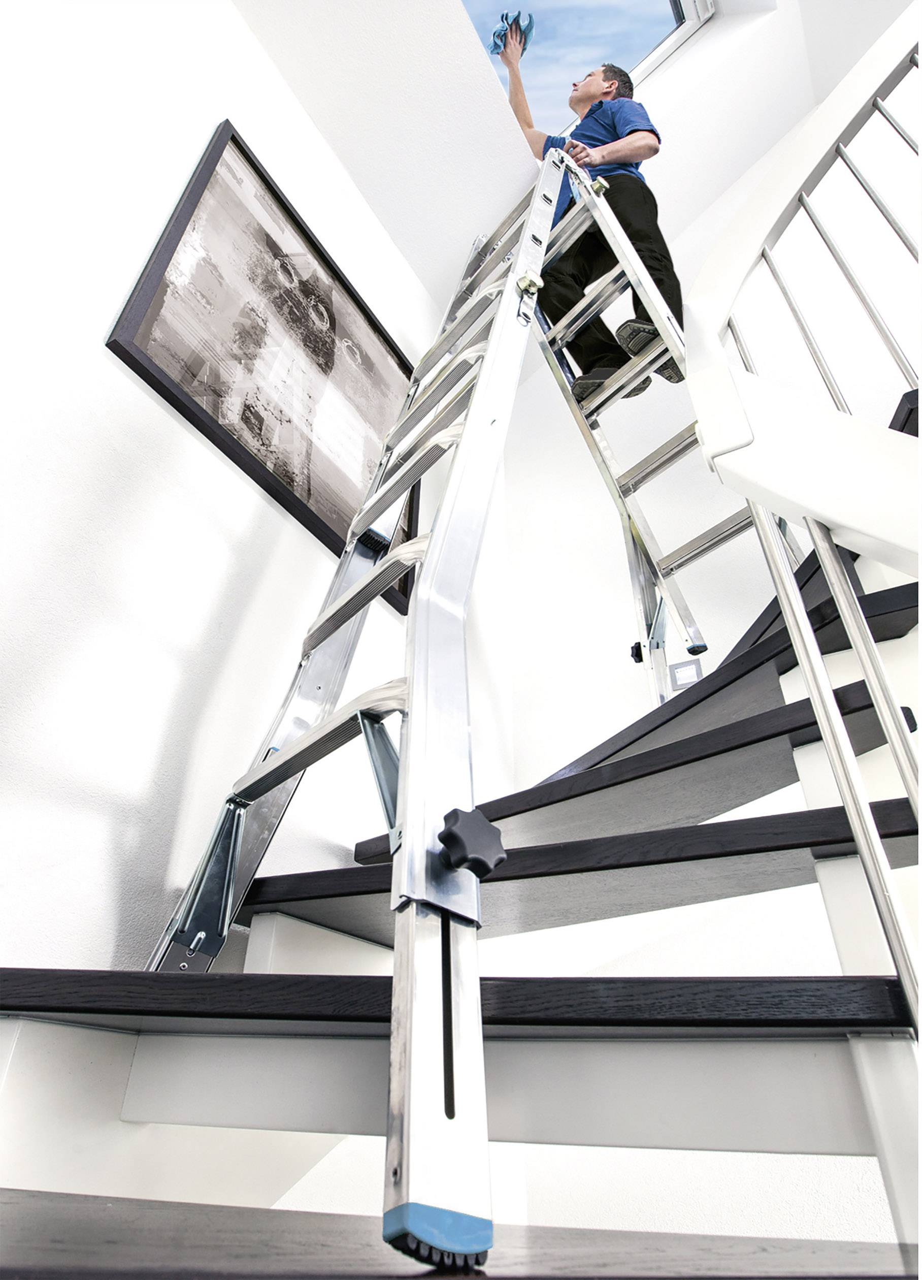 Eine Person auf einer Leiter reinigt ein Oberlicht. Die Leiter steht auf einer Treppe. An der Wand hängt ein Schwarz-Weiß-Foto.