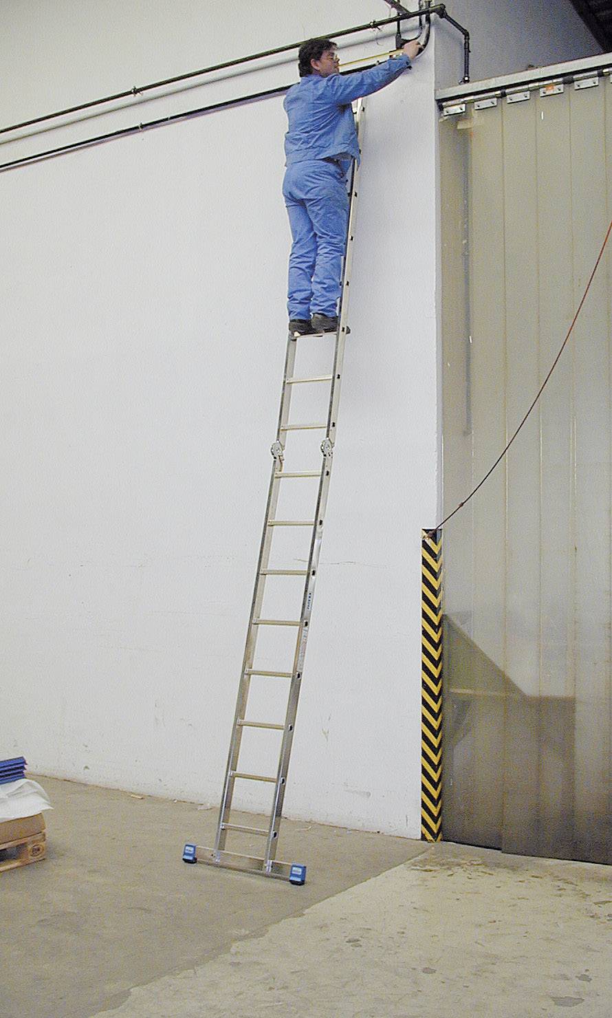 Eine Person steht auf einer hohen, ausgefahrenen Leiter und arbeitet an einer Leitung an der Wand. Die Leiter ist auf einem Betonboden platziert.