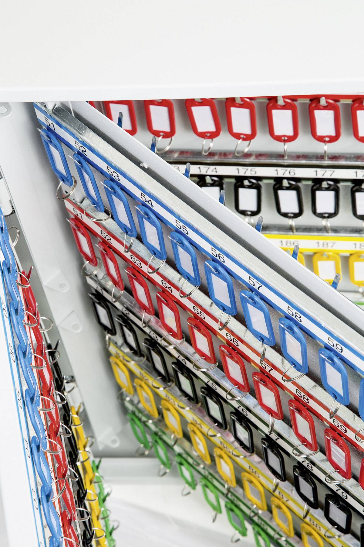 Farbige Schlüsselschilder hängen organisiert an Metallstäben in einem Schlüsselschrank. Farben: Rot, Blau, Grün, Gelb.