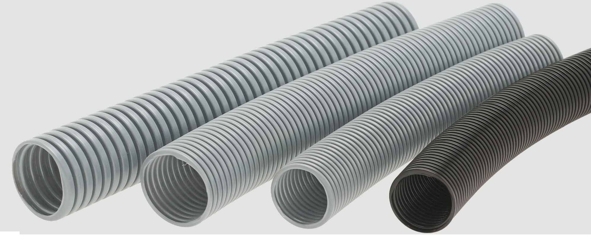 Vier flexible Kunststoffschläuche in verschiedenen Grautönen und Schwarz nebeneinanderliegend. Sie haben geriffelte Oberflächen.