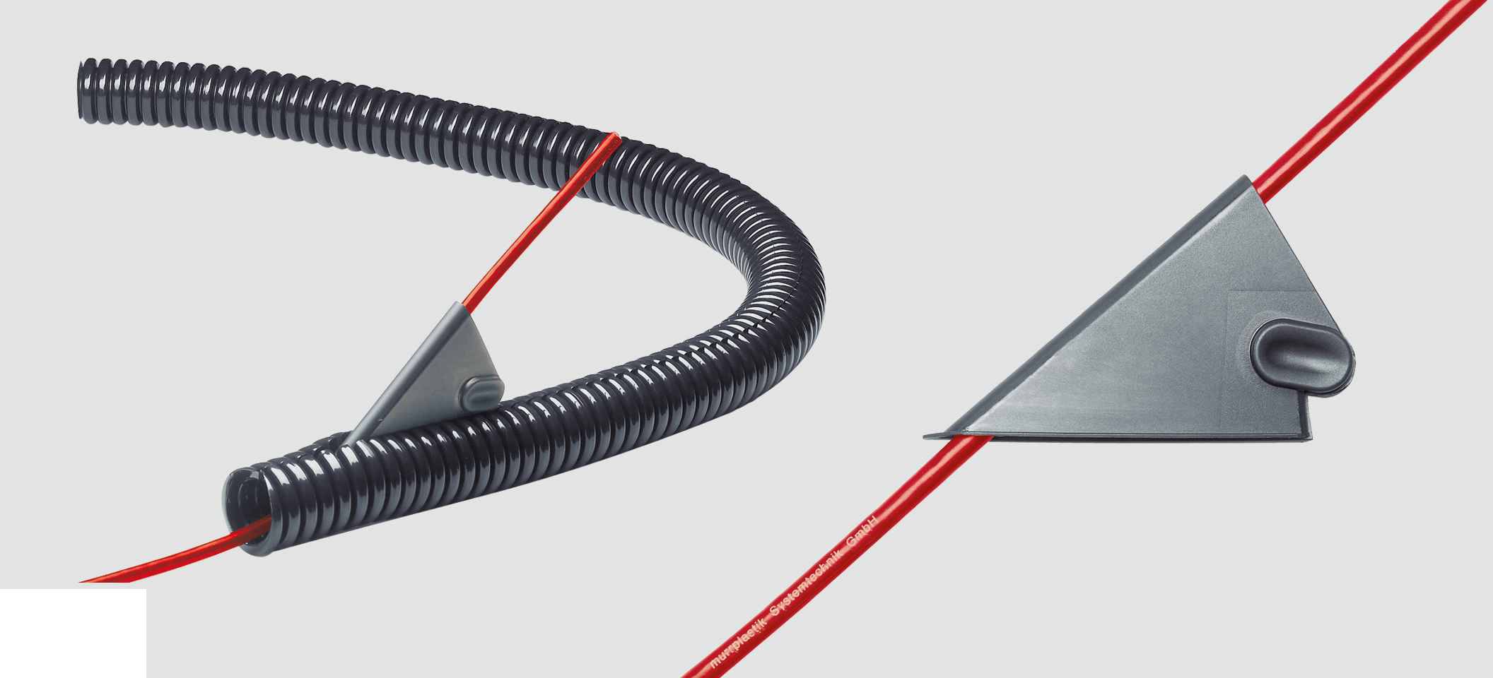 Ein roter Kabel wird durch ein flexibles, schwarzes Schutzrohr mit einem grauen Führungselement geführt.