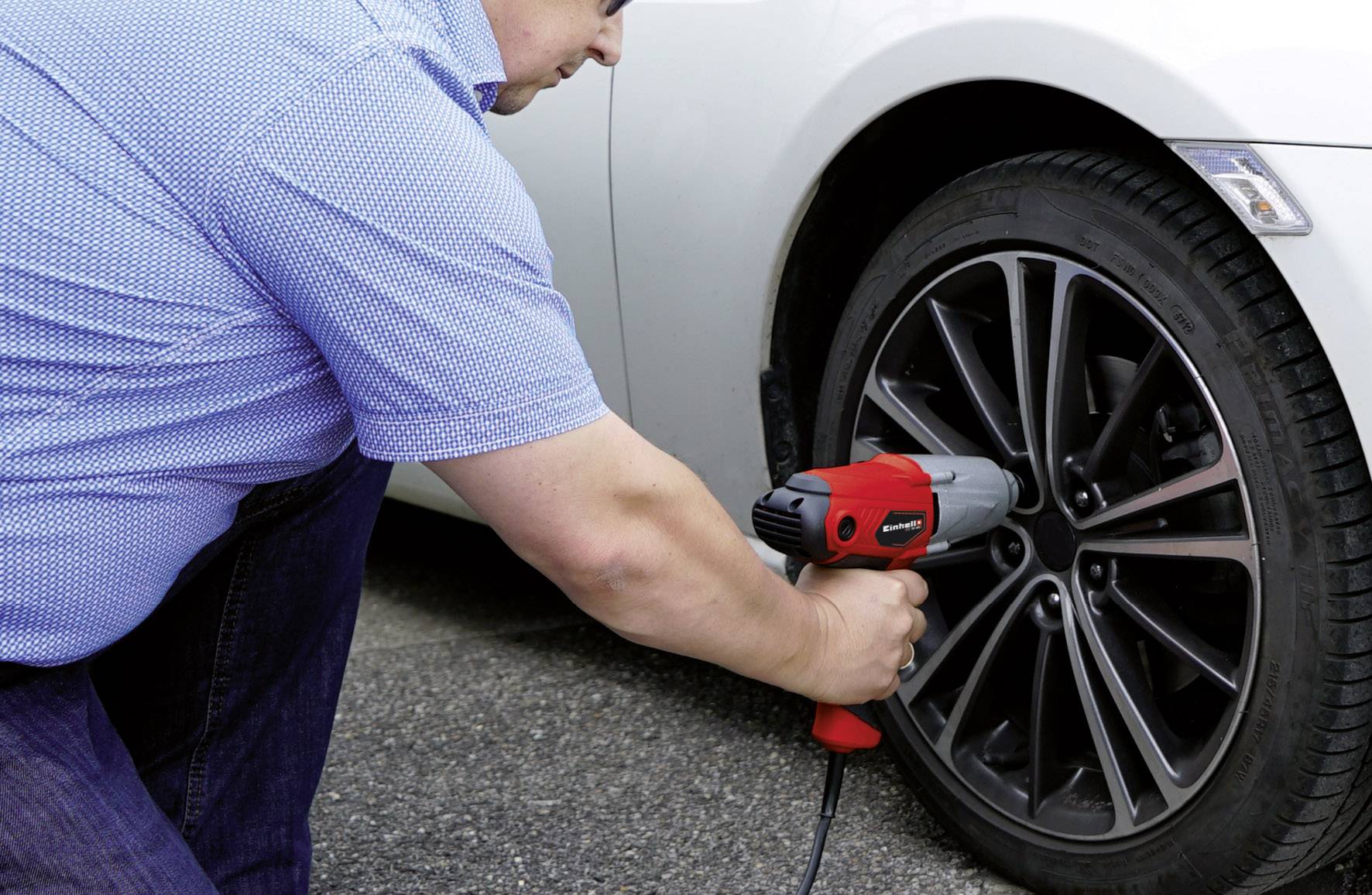 Person wechselt Autoreifen mit einem elektrischen Schlagschrauber. Die Aufnahme zeigt Nahaufnahme der Arbeit an einem Fahrzeugrad.