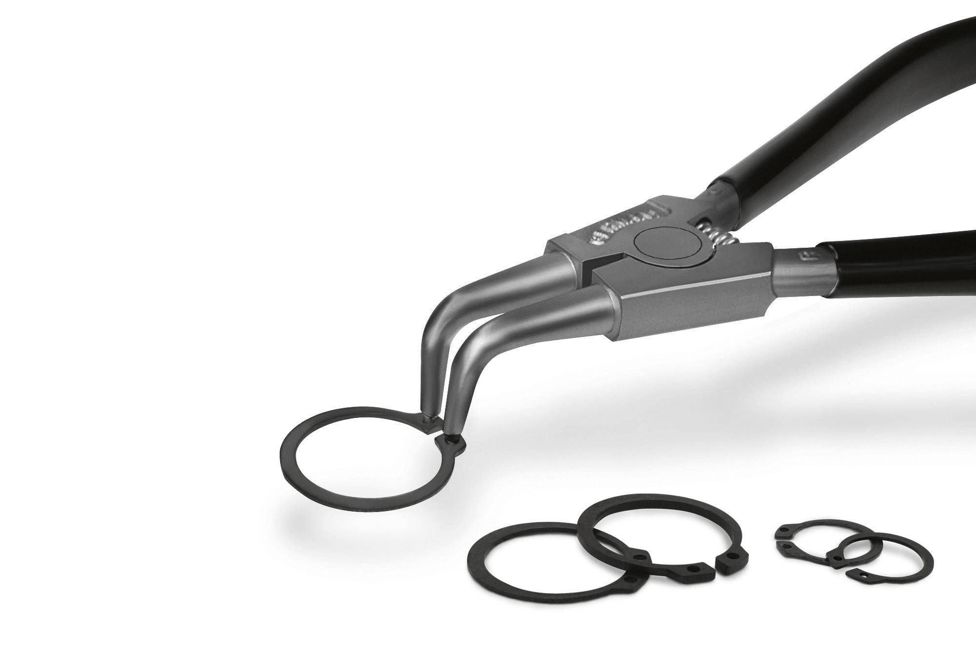 Eine Zange hält einen Sicherungsring, weitere Ringe liegen links daneben auf einer weißen Oberfläche. Werkzeuge für Reparaturarbeiten.