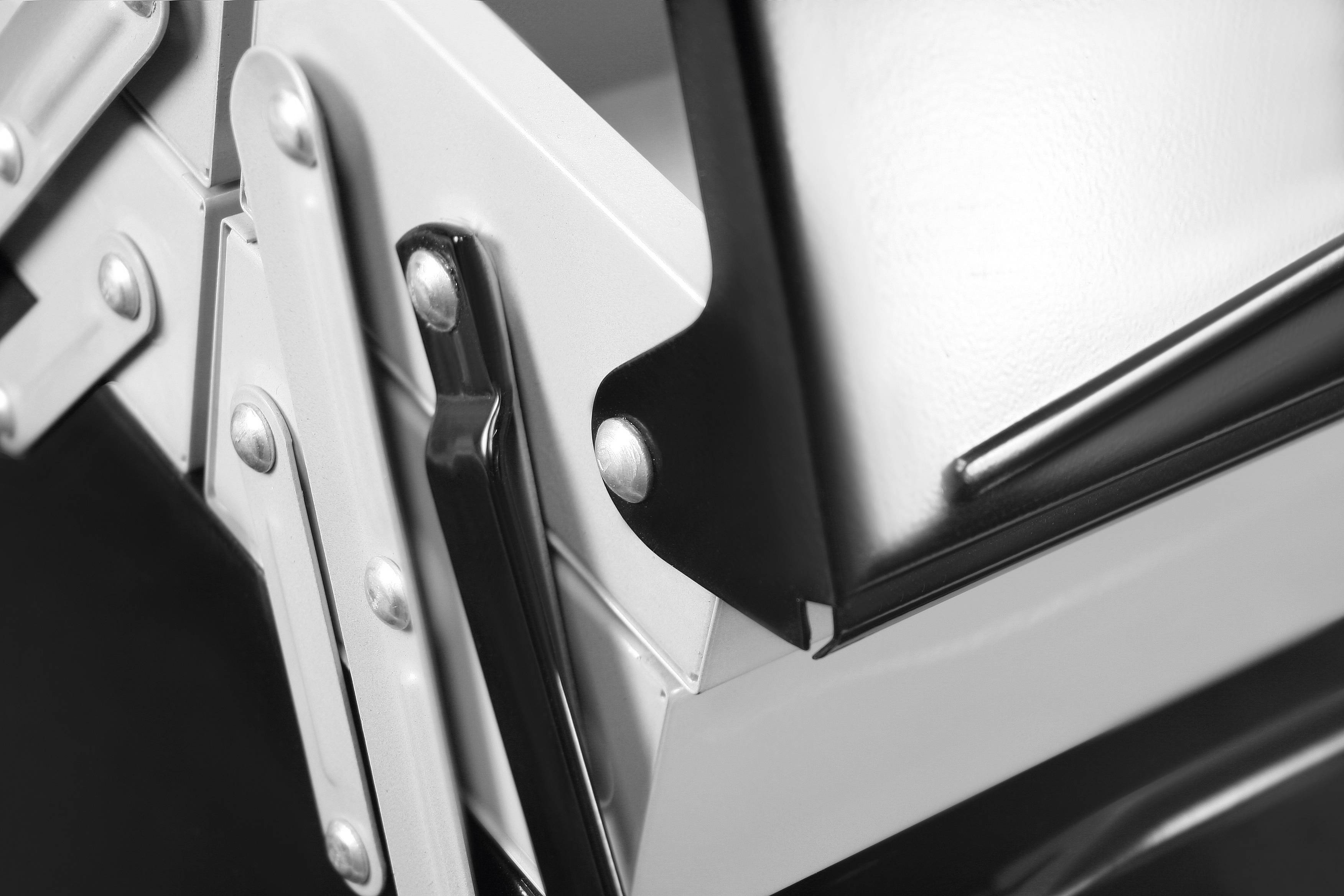 Nahaufnahme mechanischer Gelenke und Metallteile einer Maschine, schwarz-weiß, zeigt Details von Schrauben und Verbindungen.