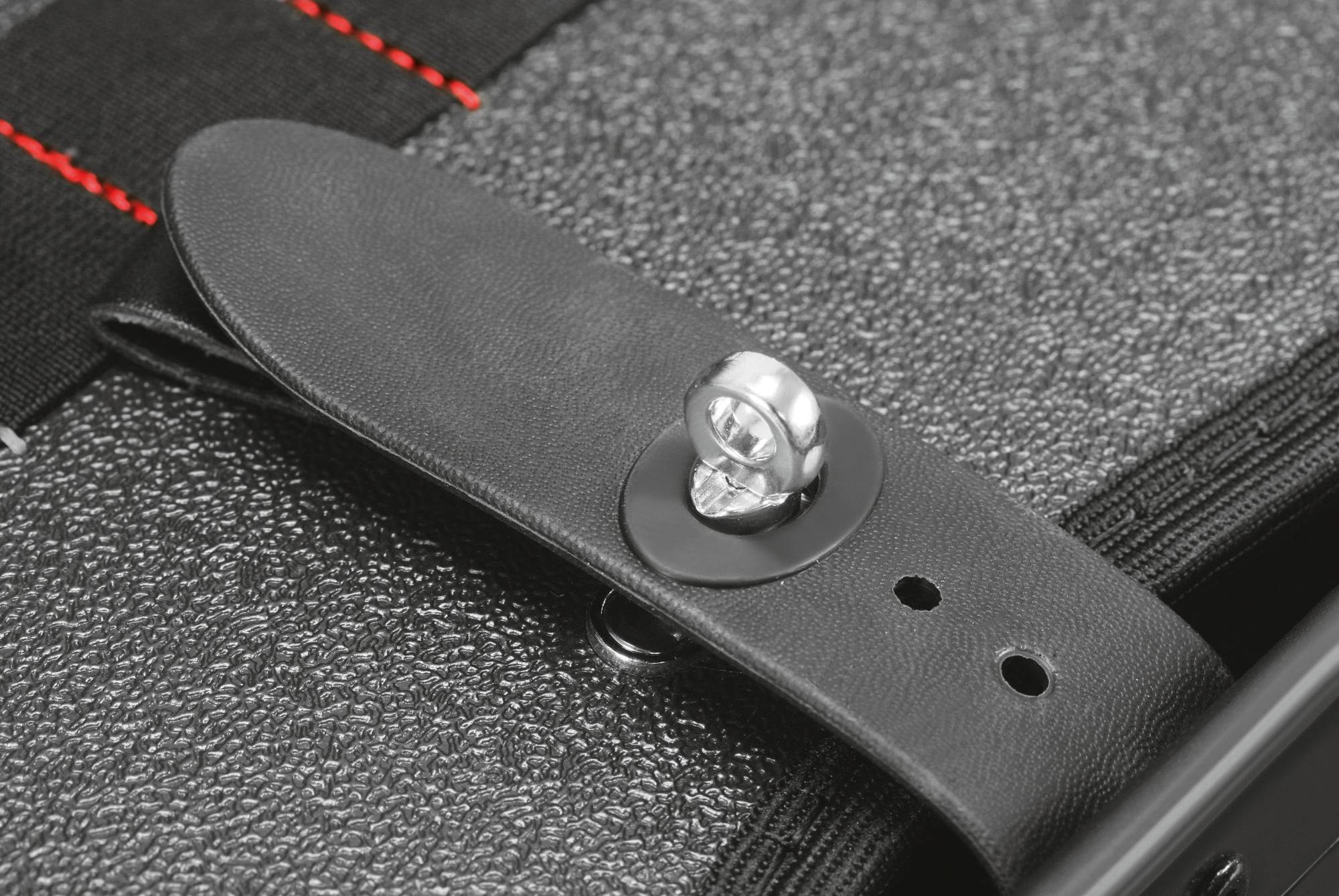 Ein Detailfoto eines Gitarrenkoffers. Ein schwarzer Lederriemen mit einem silbernen Knopfverschluss ist sichtbar.