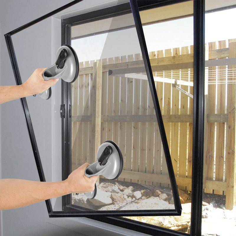 Person hält einen Fensterrahmen mit Saugnäpfen. Draußen ist ein Holzzaun sichtbar.