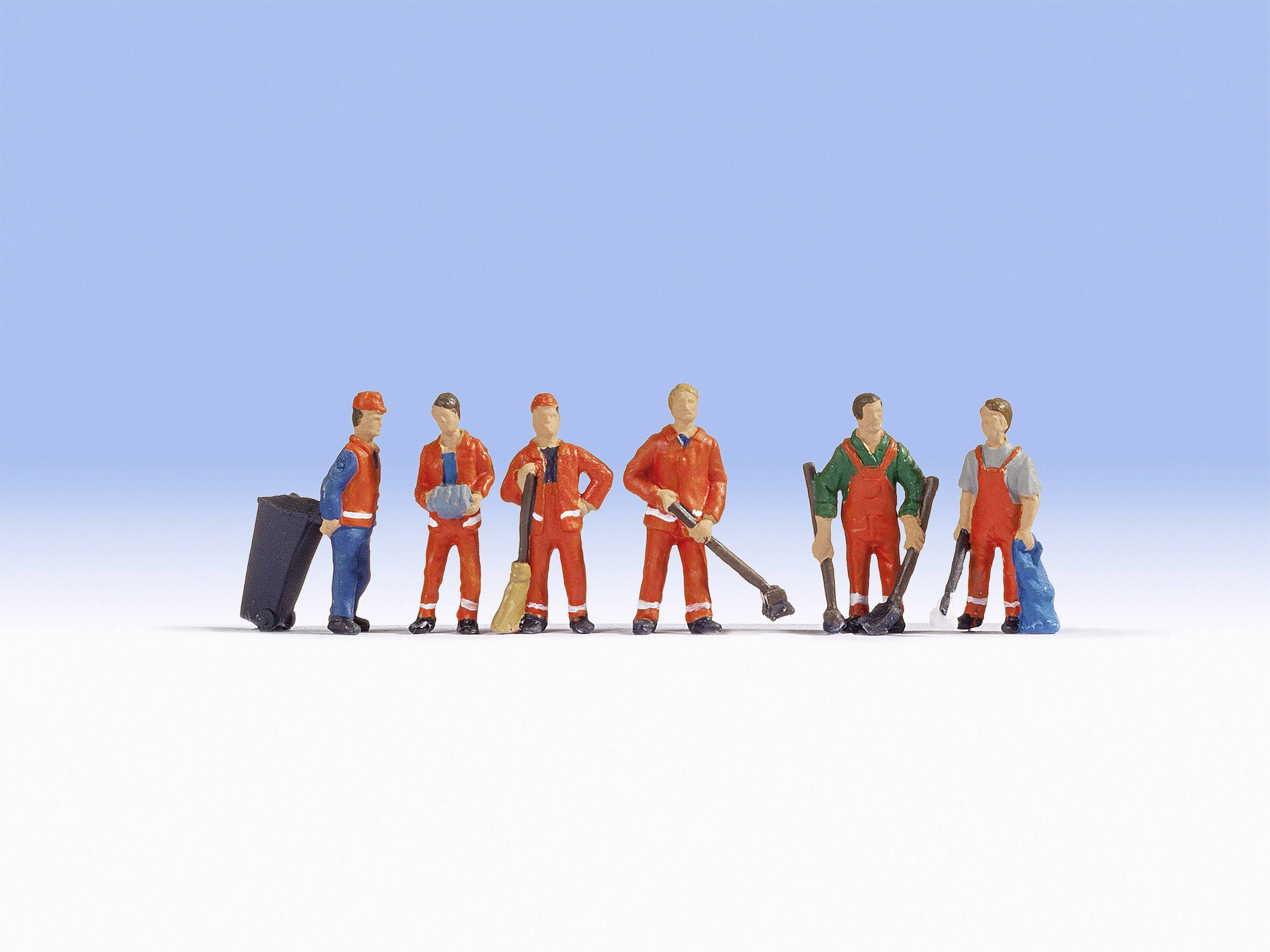 Sechs Figürchen von Arbeitern in bunten Overalls stehen in einer Reihe. Einige halten Werkzeuge wie Besen und Schaufeln.