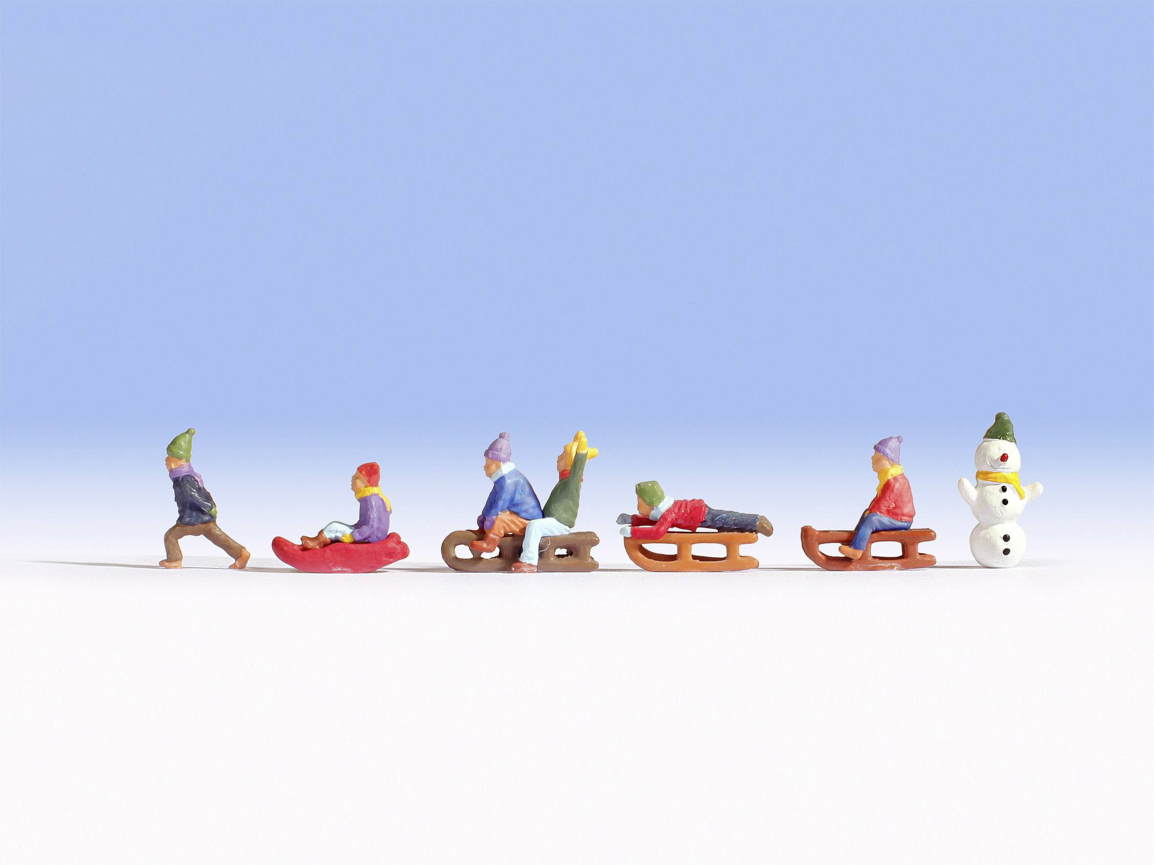 Kleine Figuren rodeln auf Schneefläche, begleitet von einem Schneemann. Einige fahren auf Schlitten, andere liegen bäuchlings. Klarer Himmel.