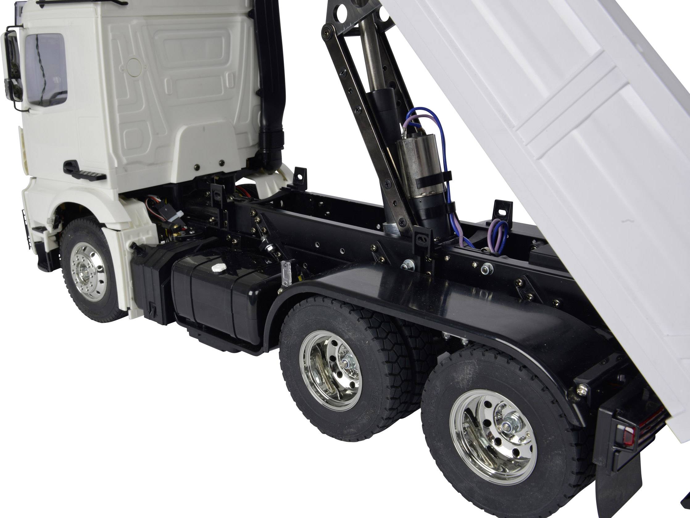 LKW mit Anhänger hebt Ladefläche an. Zeigt Hydraulikmechanismus und Reifen.