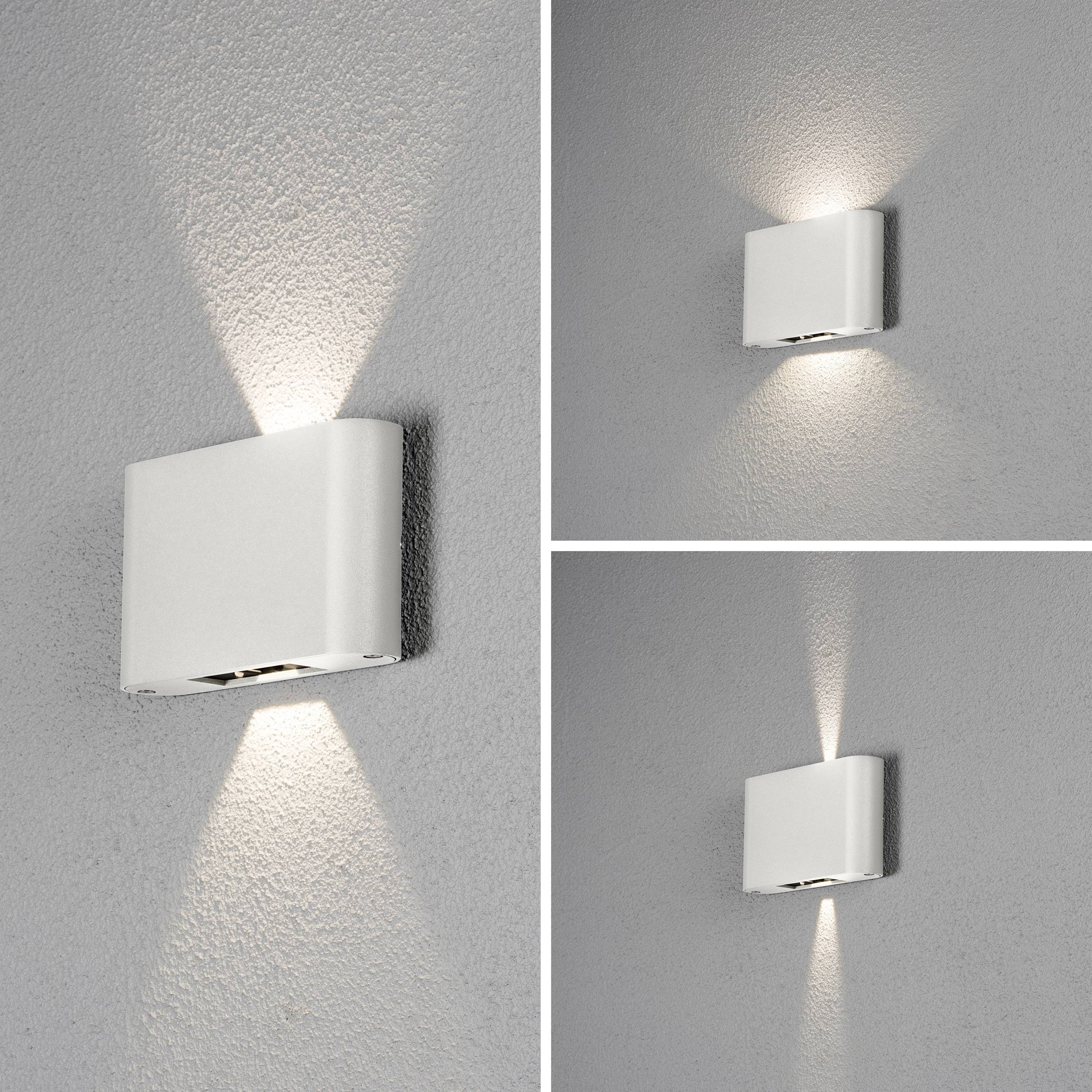 Eine moderne Wandlampe an einer grauen Wand, die nach oben und unten strahlt, beleuchtet die Umgebung mit sanftem Licht.