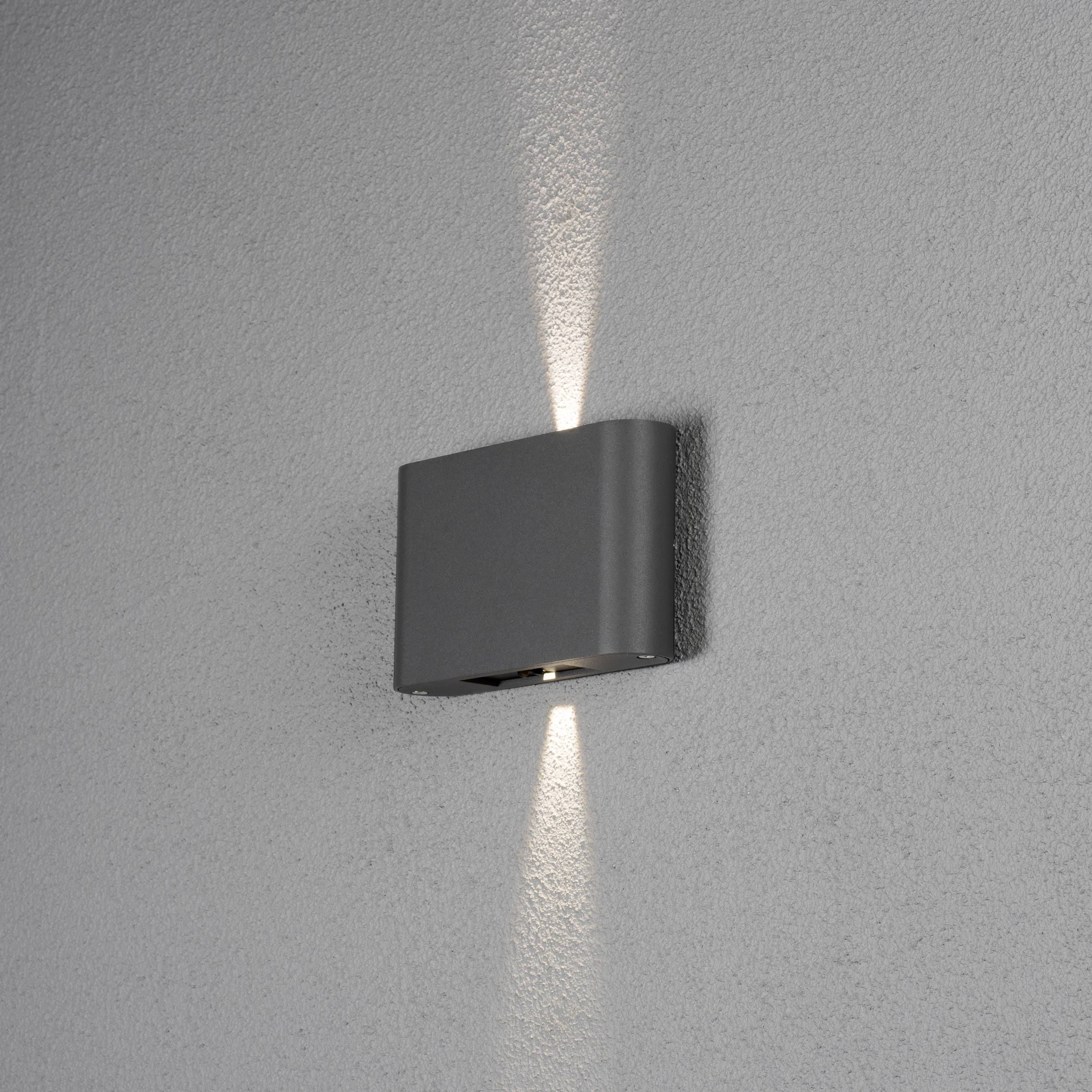 Moderne Wandlampe, die nach oben und unten Lichtstrahlen auf eine graue Wand projiziert. Minimalistisches Design, rechteckige Form.