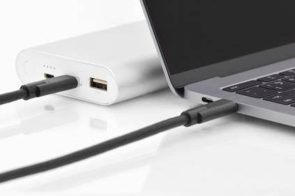 Ein Laptop ist über ein USB-Kabel mit einer tragbaren Powerbank verbunden.