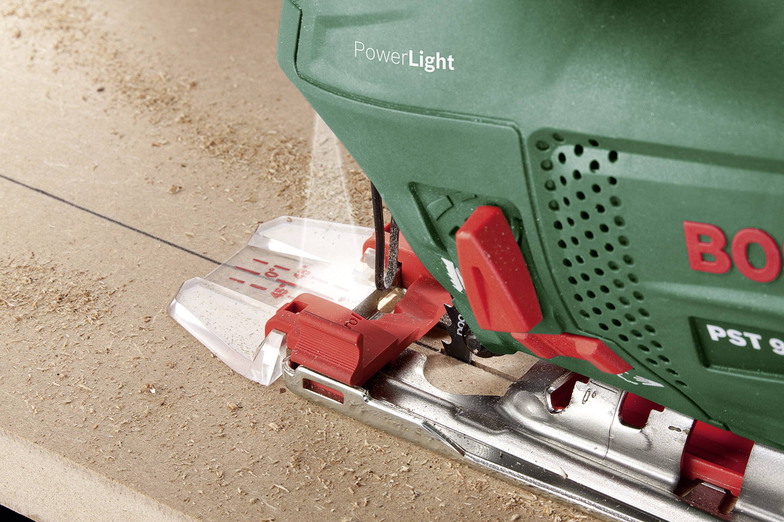 Eine grüne Stichsäge der Marke Bosch schneidet präzise über eine Holzoberfläche. Eine eingebaute Lampe beleuchtet den Schnittbereich.