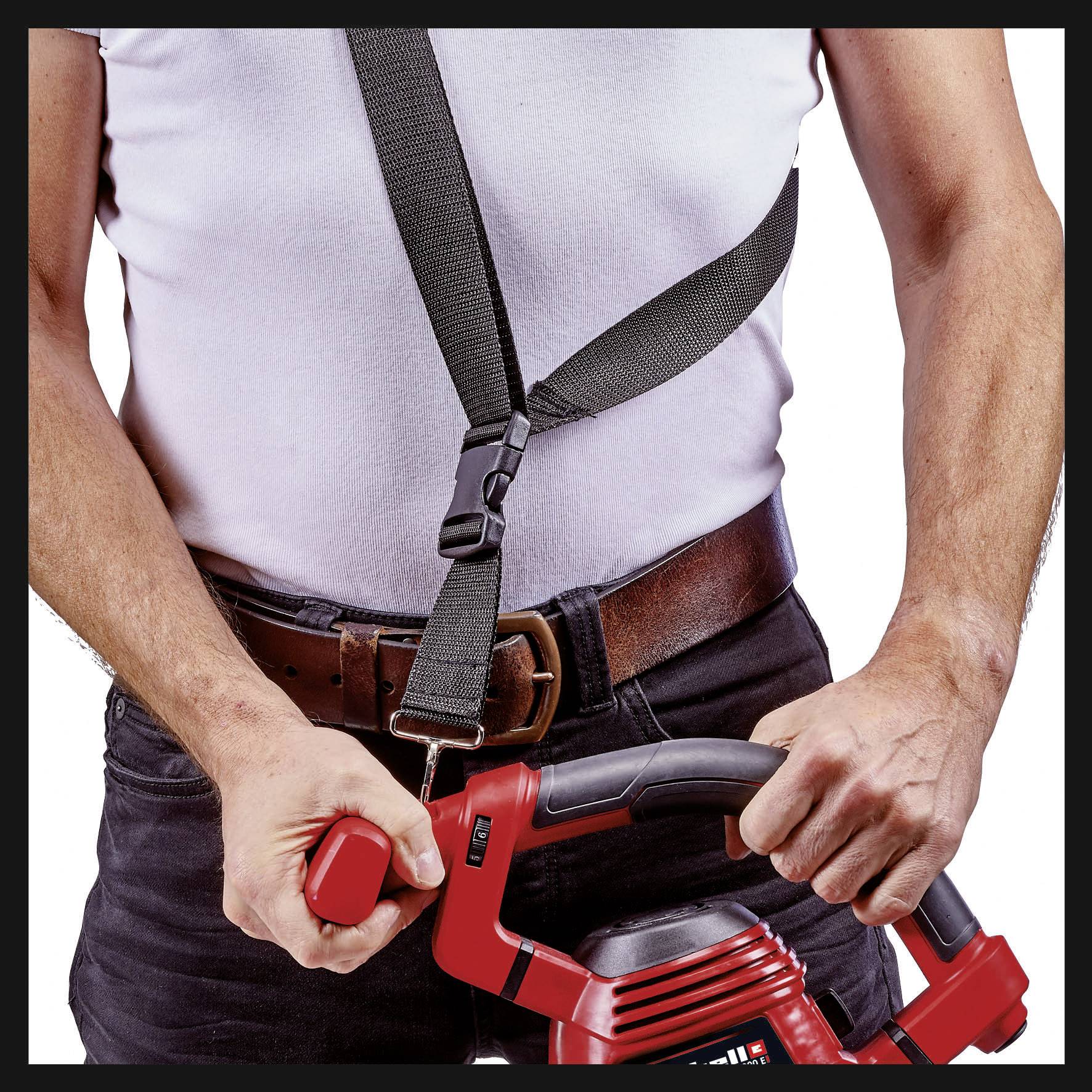 Mann in weißem T-Shirt halt eine rote Maschine mit beiden Händen, wobei der Fokus auf seiner Handhaltung liegt.