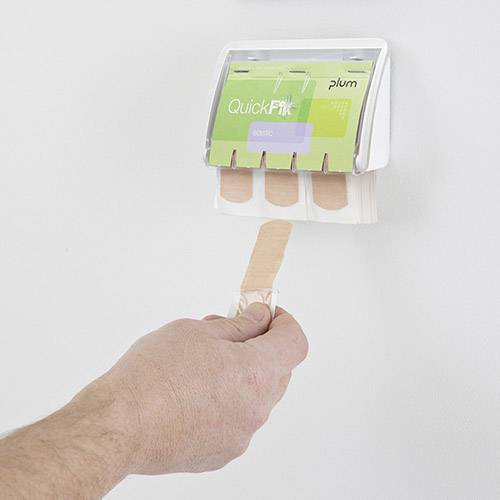 Ein Hand zieht ein Pflaster aus einem Wandspender mit der Aufschrift 'QuickFix'. Der Spender ist an einer weißen Wand montiert.
