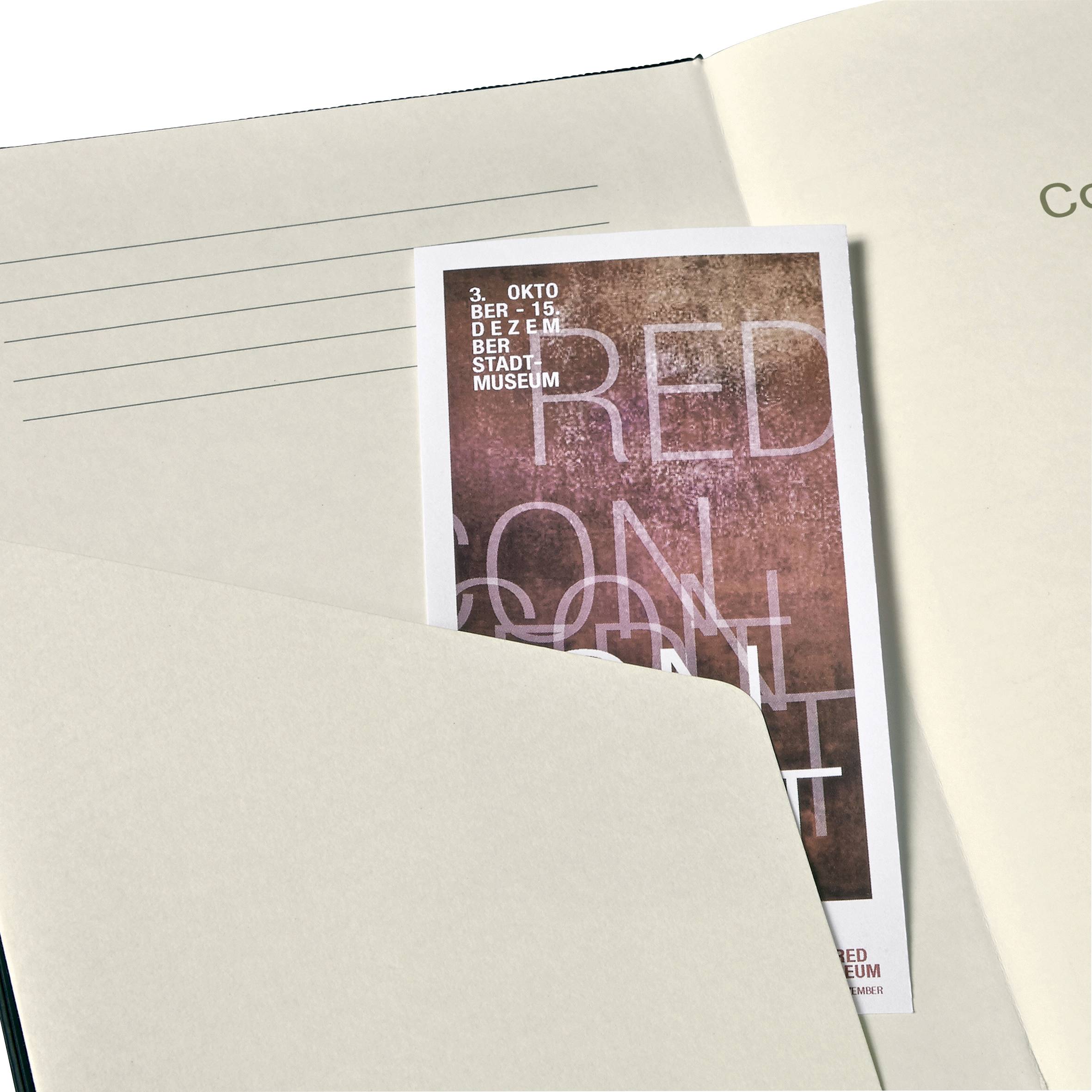 Ein Ticket mit rotem, texturiertem Hintergrund steckt in einem Buch. Darauf steht: '30. OKTOBER - 15. DEZ, STADTMUSEUM'.