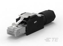 Ein RJ45-Stecker, teils umhüllt mit schwarzem Kunststoff, liegt auf einer weißen Unterlage. Das Logo von TE Connectivity ist sichtbar.