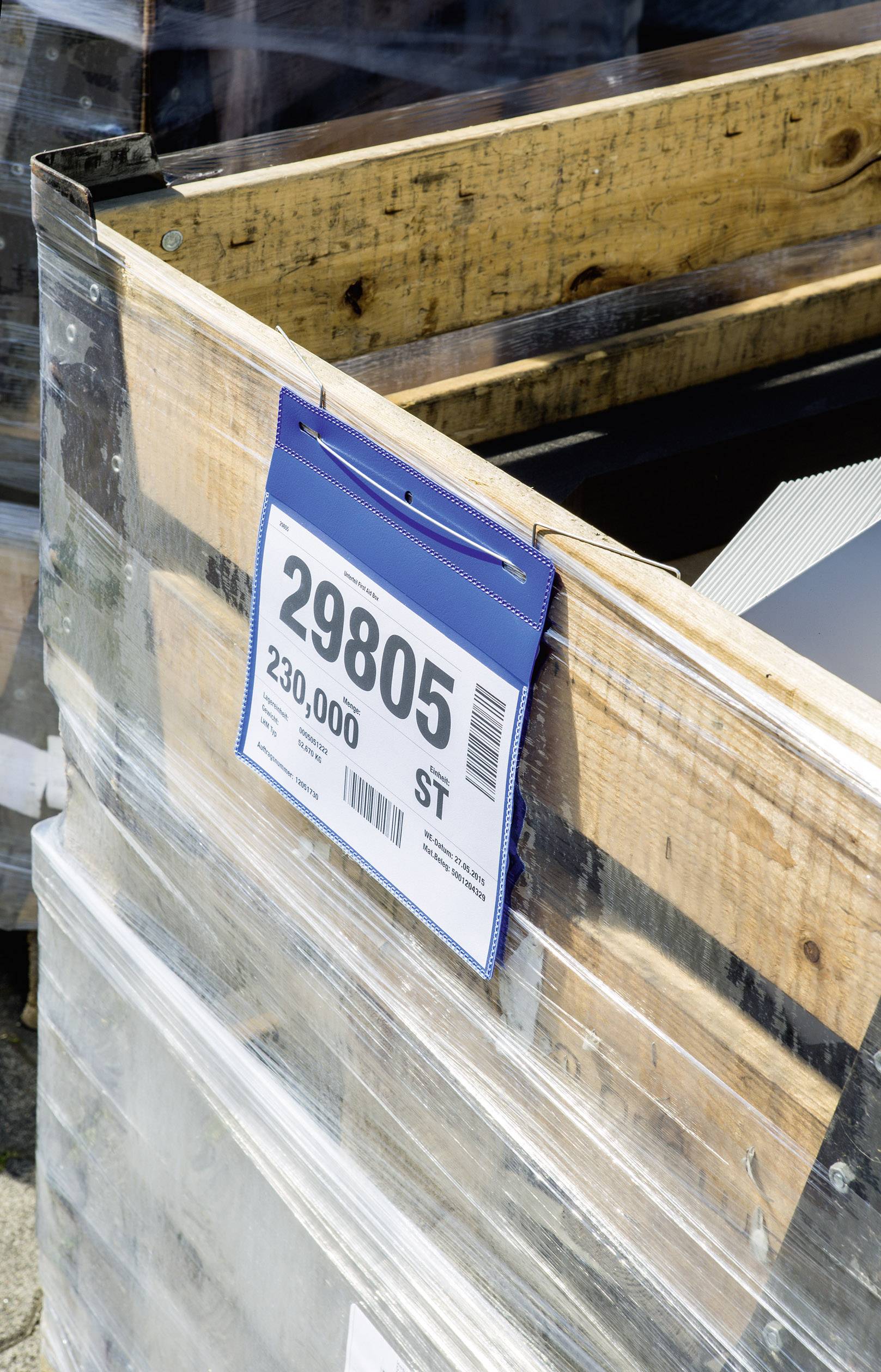 Ein mit Folie umwickelter Holzkasten mit einem Schild. Auf dem Schild steht '29805 230,000 ST', was auf Inhalt oder Stückzahl hinweist.
