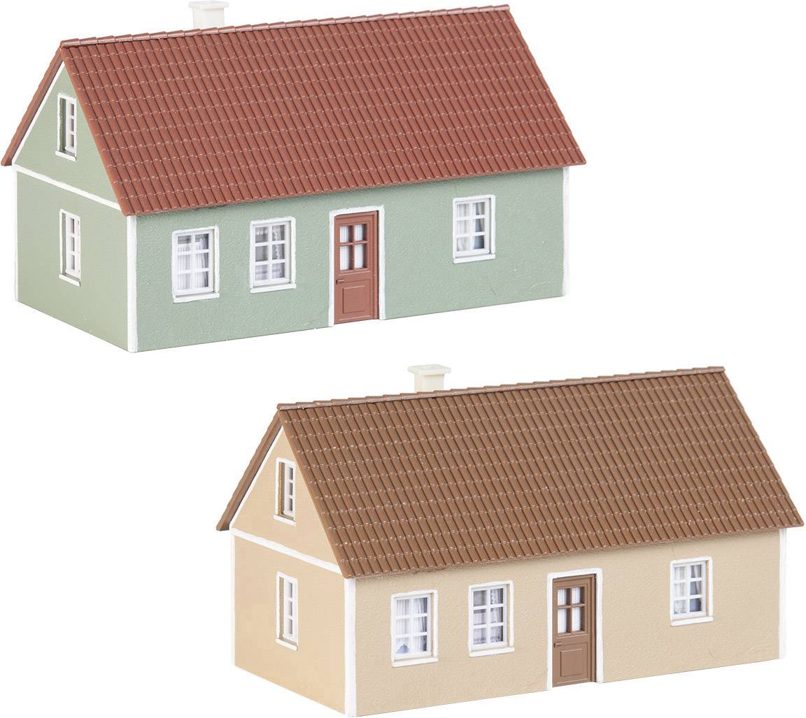 Zwei Modellhäuser mit rotem Dach, ein grünes und ein beiges Gebäude, nebeneinander stehend, zeigen typische Architekturmerkmale.