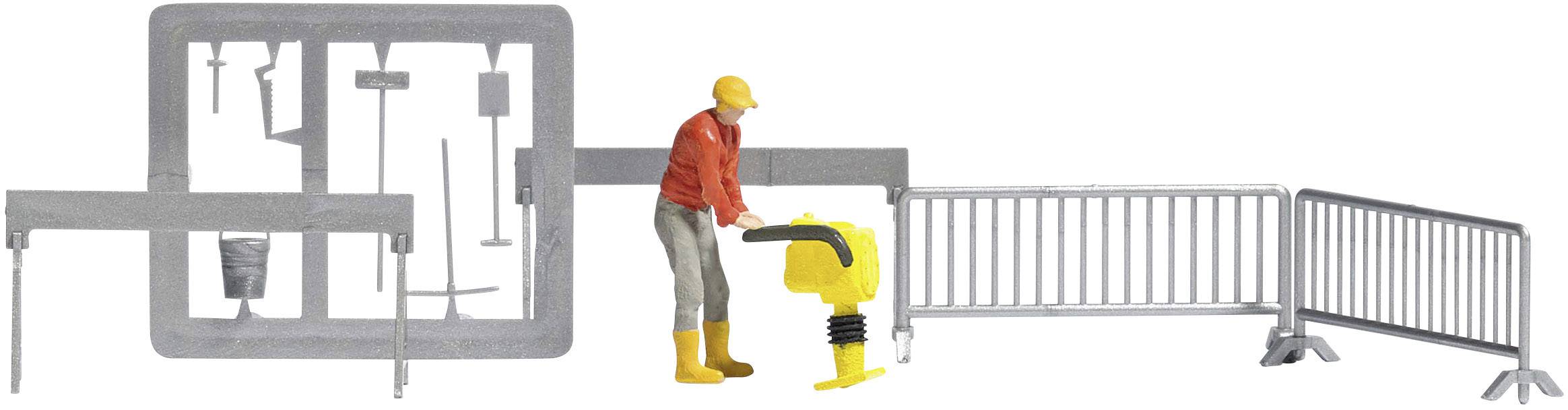 Ein Bauarbeiter in roter Jacke steht neben einem gelben Baugerät, umgeben von silbernen Absperrgittern, die eine Baustelle sichern.