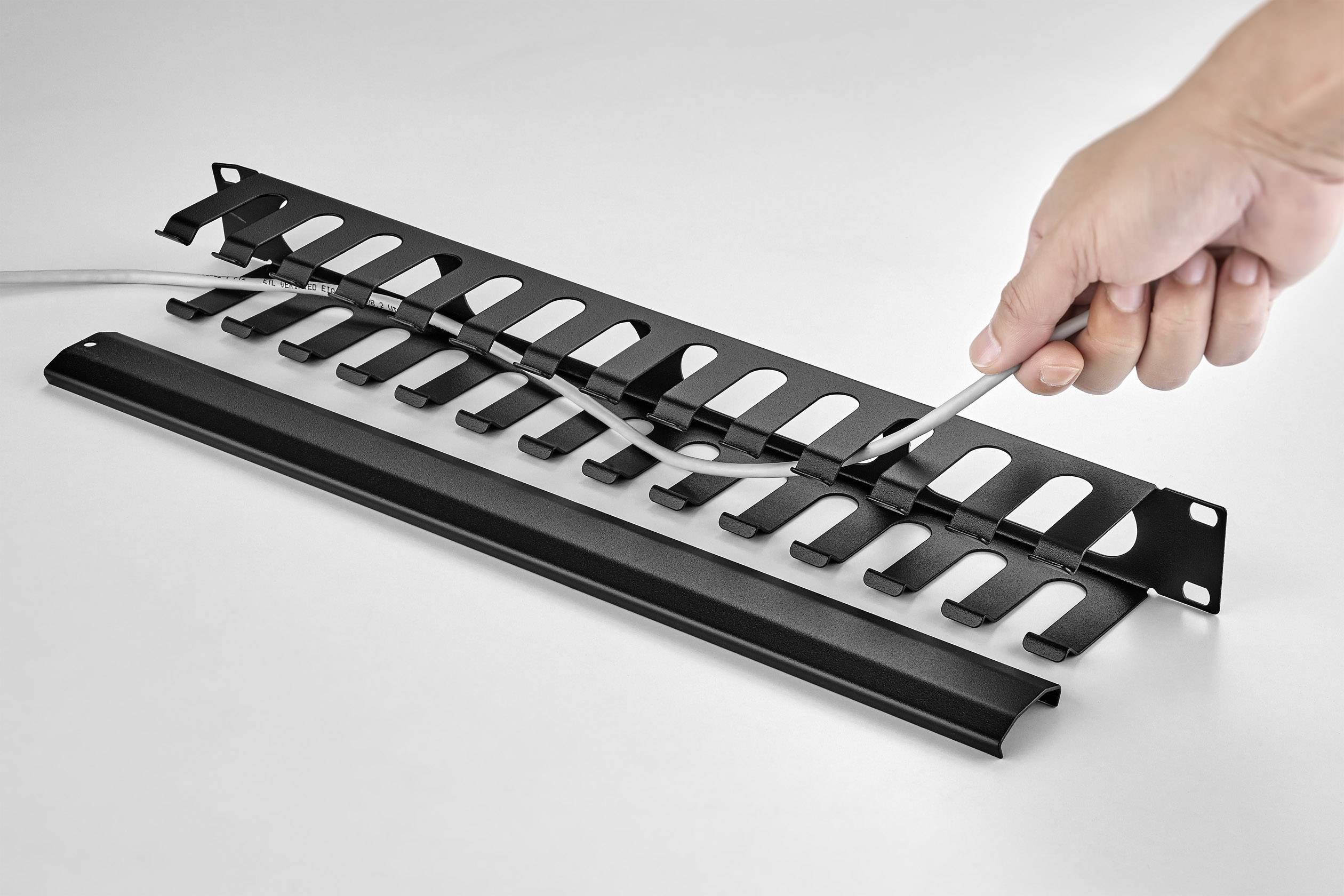 Ein Hand ordnet Kabel in einem schwarzen Kabelmanagementsystem mit mehreren Haken.