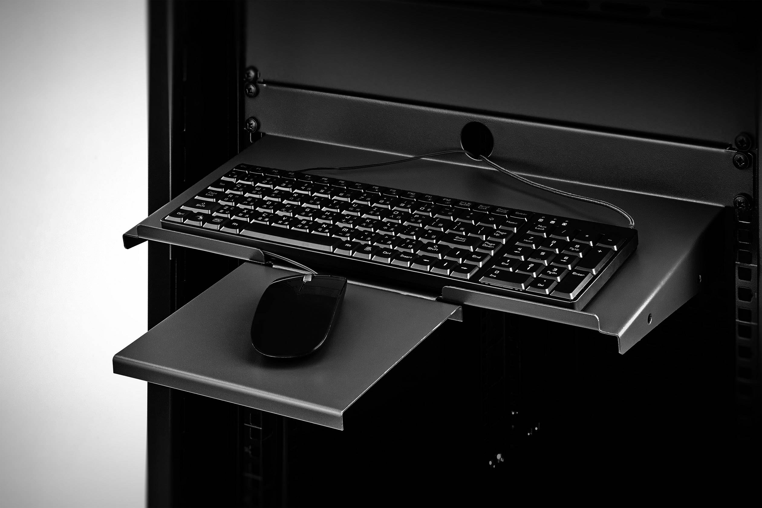Eine schwarze Tastatur und Maus auf einem ausziehbaren Regal in einem Server-Rack, bereit für die Wartung oder Bedienung.