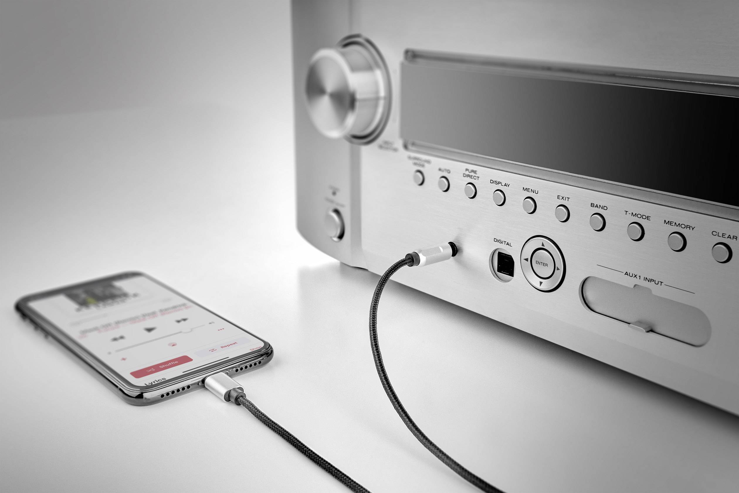 Ein Smartphone ist über ein Kabel mit einem Verstärker verbunden, zeigt einen Musik-Player auf dem Display.